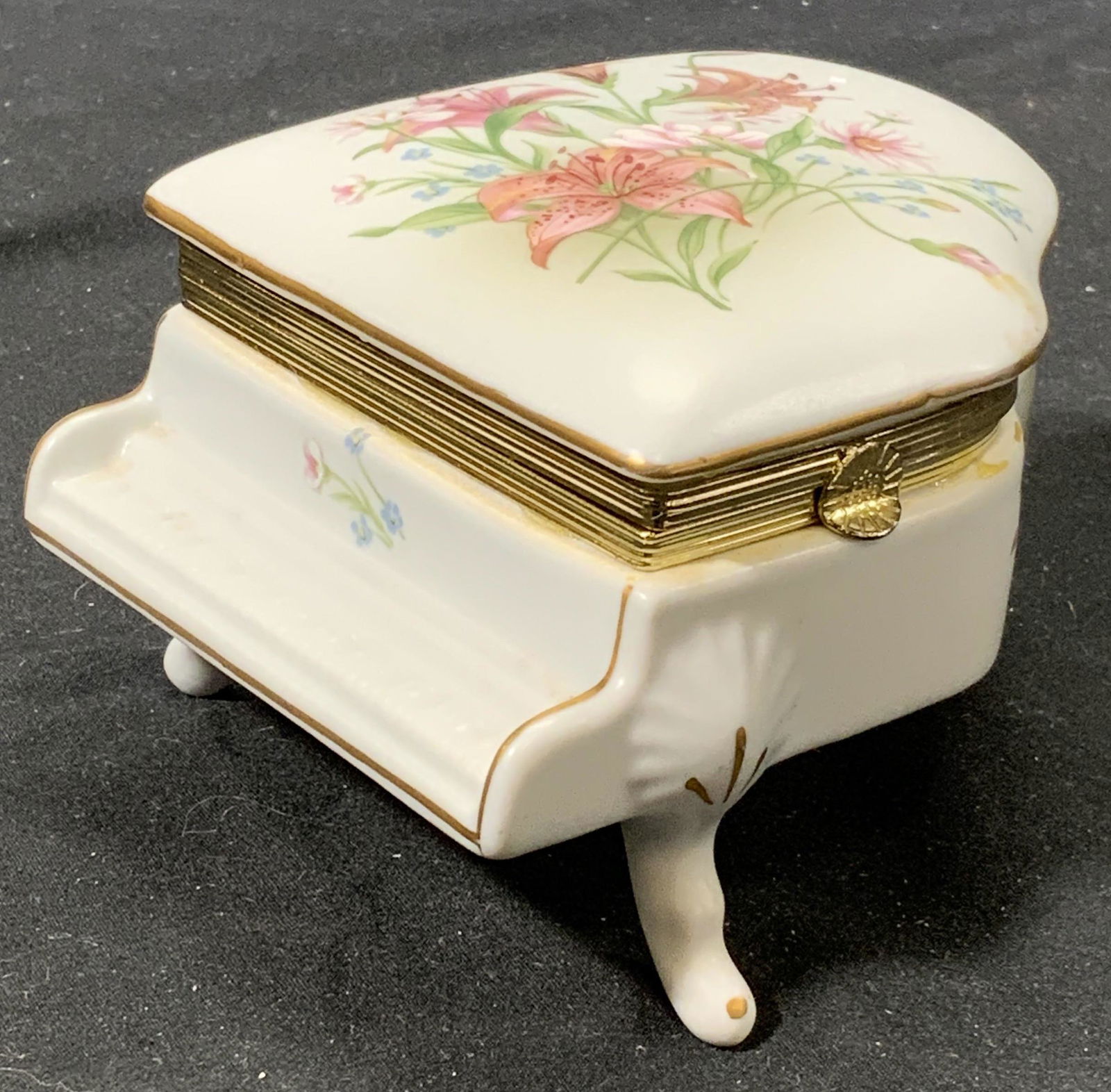 COR Day Lily Nutcracker Porcelain Music Pill Box: Signed vintage COR porcelain Day Lily floral motif music box in the shape of a piano. In good condition, music plays when box is opened and key is wound. . Measures approx. 4.75 x 3.5 x 2.5 inches. CO