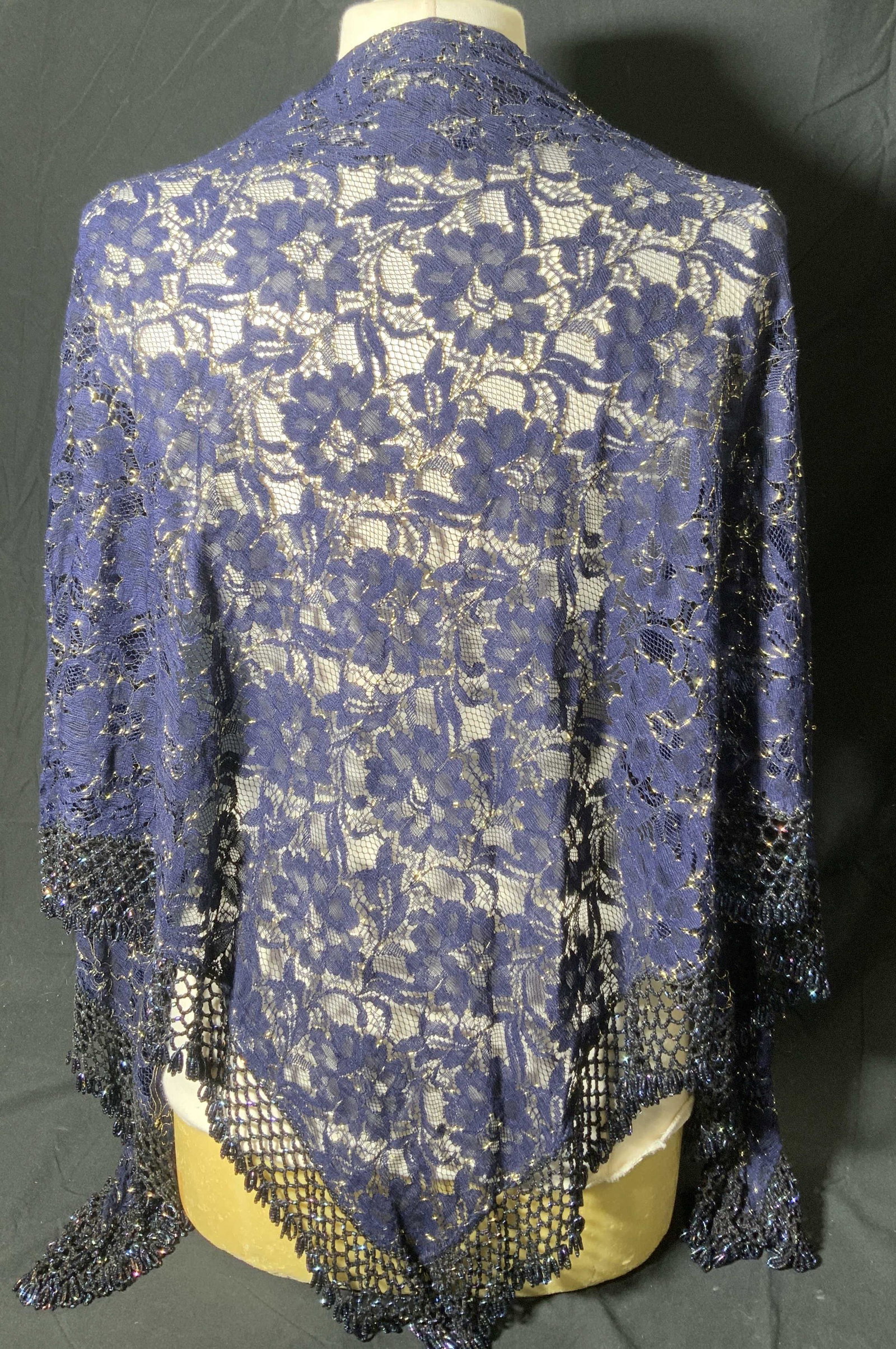 Navy Blue Beaded Floral Lace Shawl: Navy blue floral lace shawl with beaded trim and gold thread detail. Measures approx. 70 inches long. In good condition. Ladies shawl, ladies blue shawl, ladies beaded shawl, ladies floral shawl, ladi