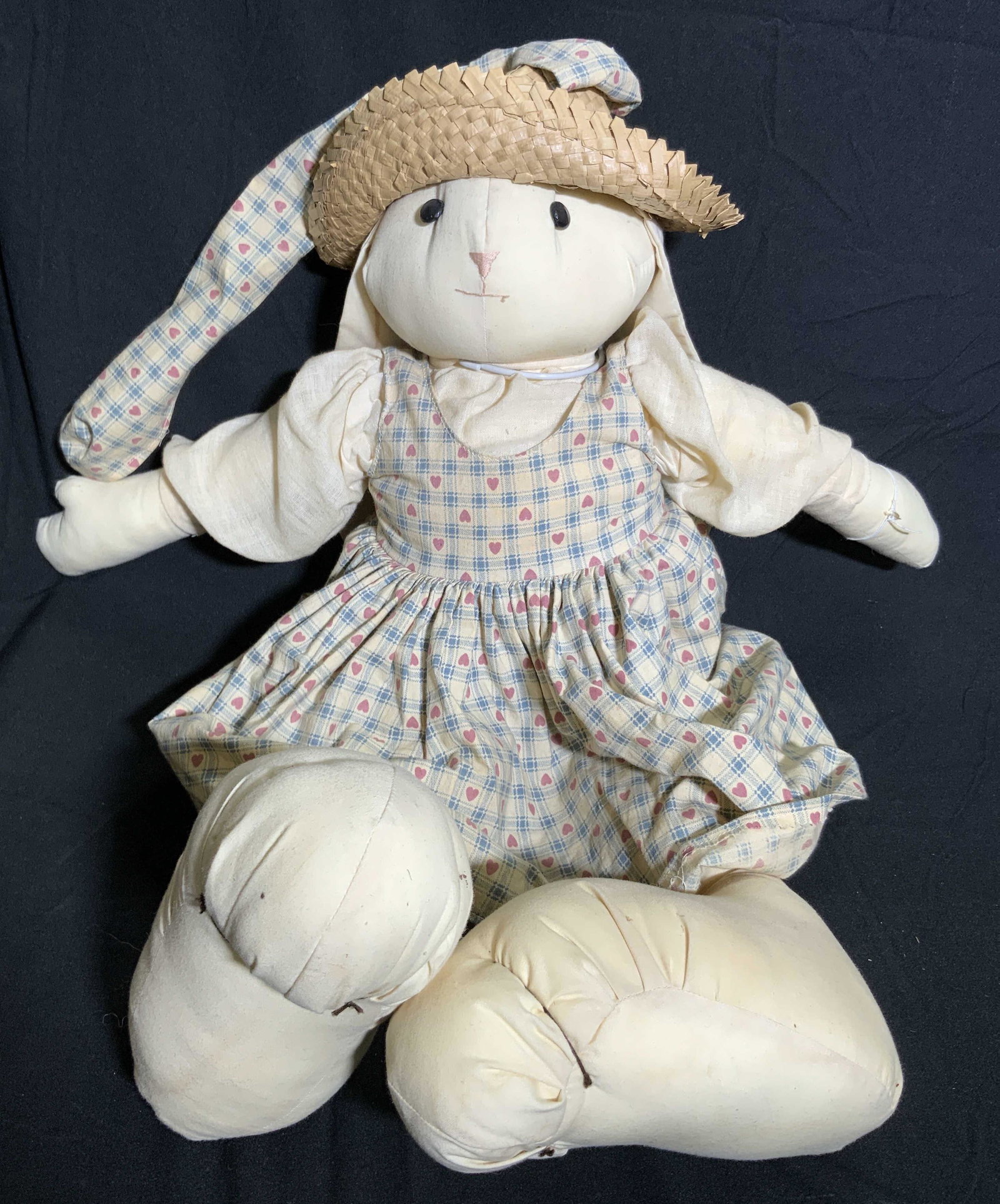 Vintage Handmade Stuffed Rabbit W/ Dress Doll: A vintage stuffed rabbit doll. Appears to be handmade. The rabbit wears a hat with ribbon and a dress. Primarily off white, pink, yellow, and blue hues. Rabbit is affixed to a KAISER metal stand. Rabb