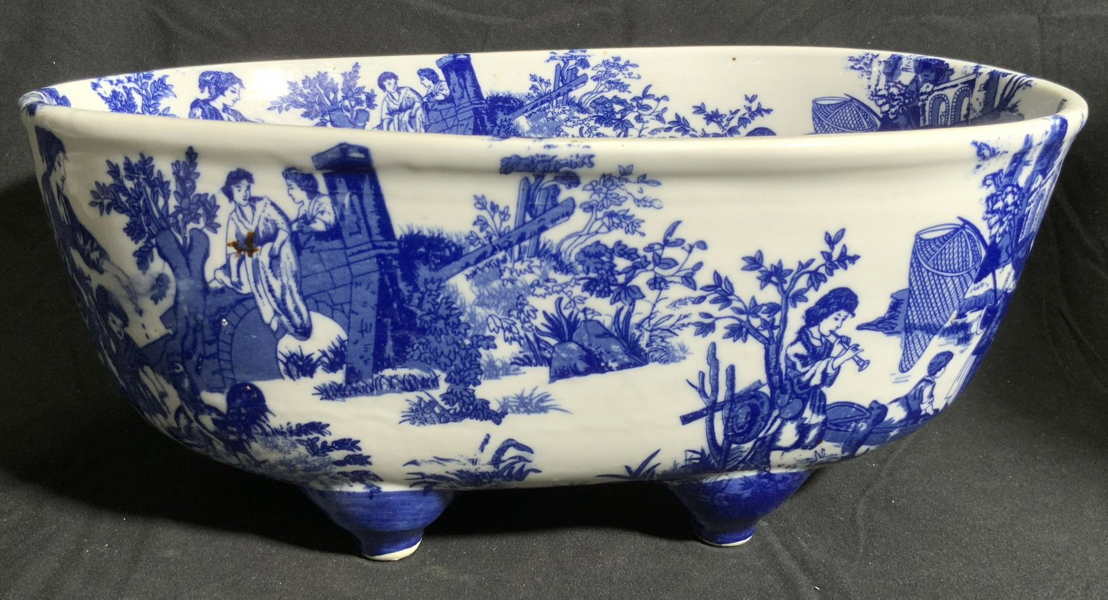 VICTORIA WARE IRONSTONE Vintage Centerpiece Bowl: A vintage, possibly antique, blue and white ironstone centerpiece bowl. Designs depict people in various nature settings. Four feet to underside. Underside stamped VICTORIA WARE IRONSTONE. Thick walle