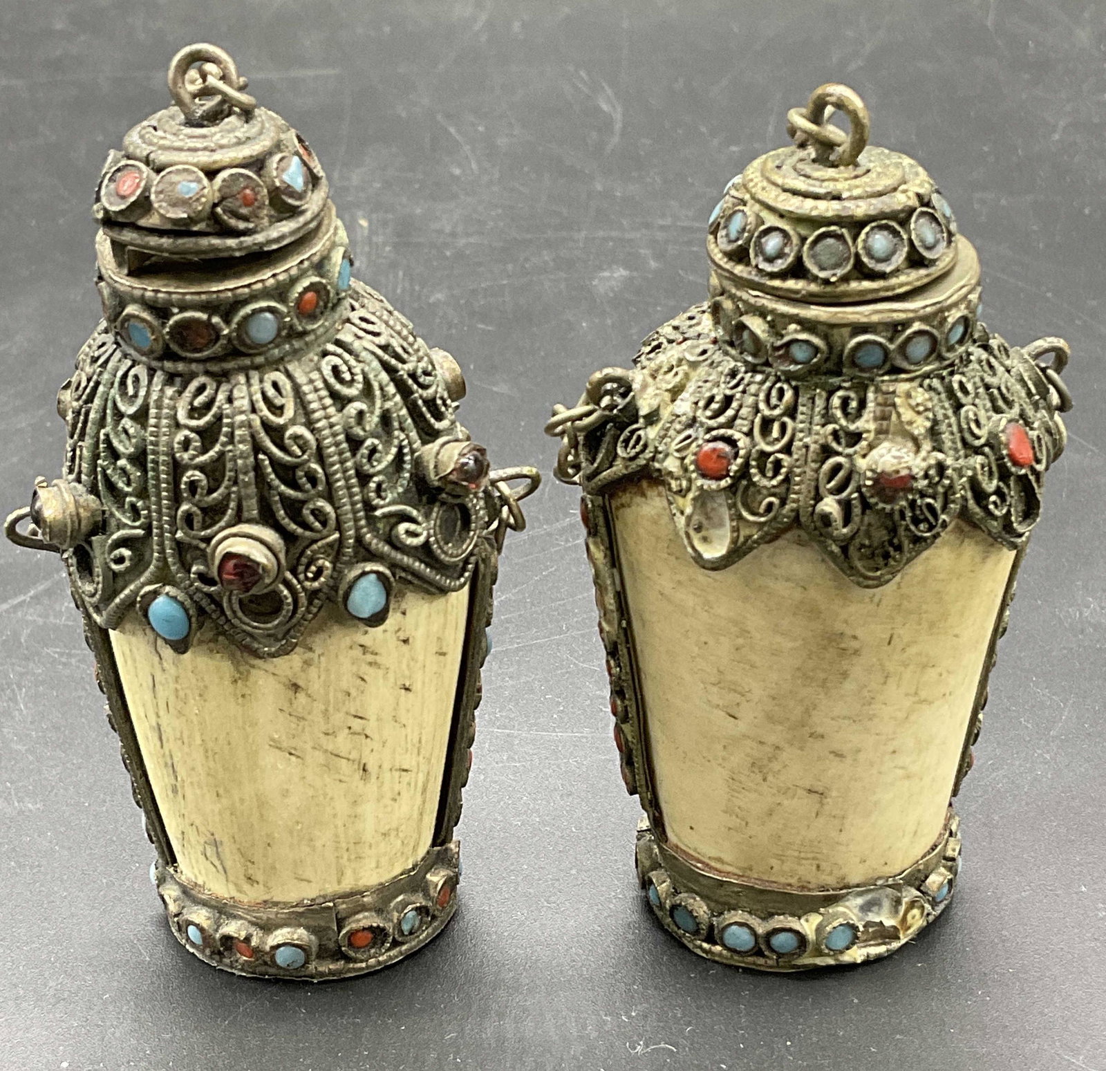 Lot 2 Vintage Bone Snuff Bottles: Pair of bone snuffers detailed with glass Cabochon beads and metal inlay. Measures approx 2.5 x 2 inches. Significant wear to pieces consistent with age and use of pieces. Bent ares on pieces. Wear to