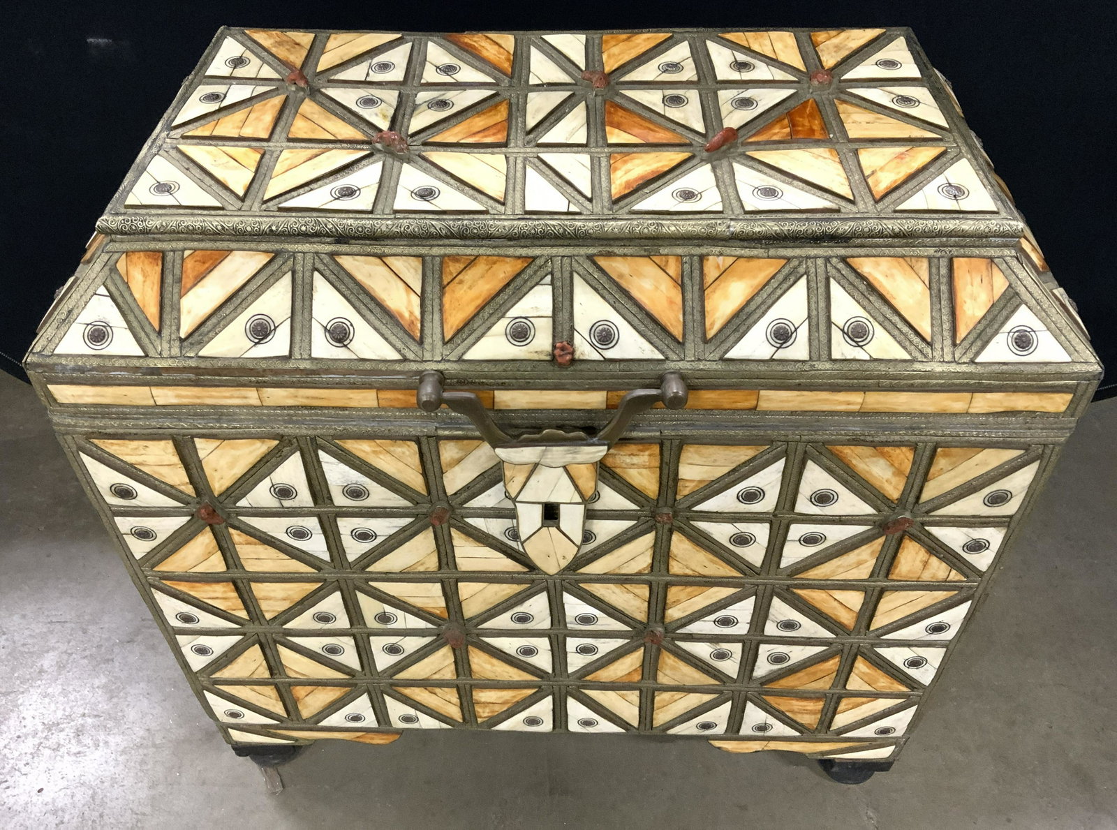 Vintage Bone Mosaic & Metal Lidded Chest 3ft Long: Chest is vintage possibly antique. Exterior has geometrically detailed bone mosaic. Exterior has small red toned areas, possibly red coral. Chest has black toned feet. Each side has brass and bone mos