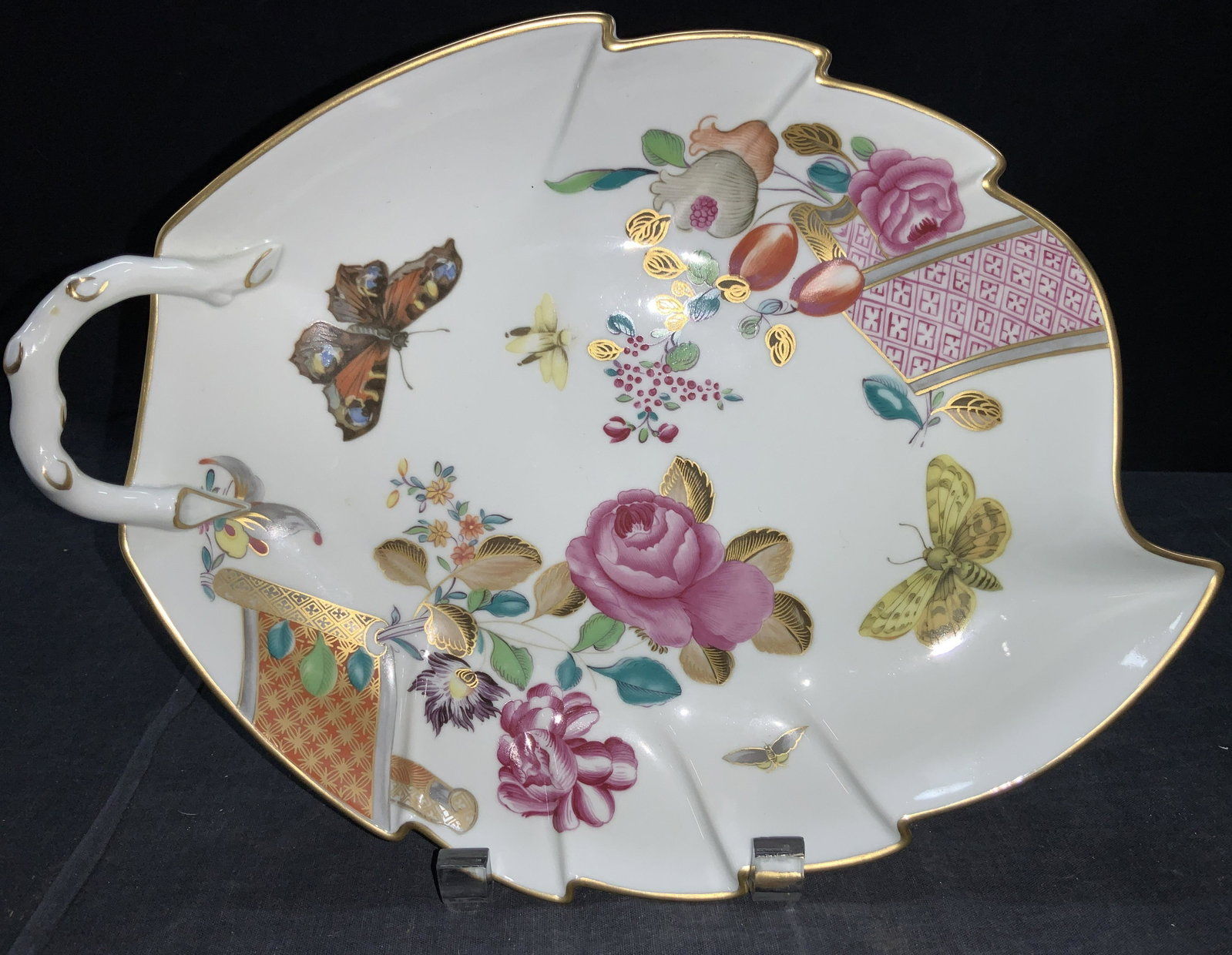 MOTTAHEDEH Porcelain Chinoiserie Painted Plate: A porcelain Chinoiserie painted plate in the shaped of a leaf with gold gilt rim and gold accents throughout the center designs. Designs depict flowers with insects. Marked on underside Mottahedeh, VA
