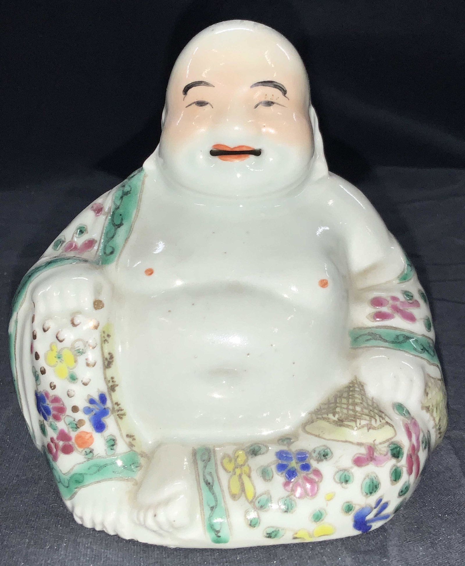 Vintage Painted Porcelain Buddha Figure: A vintage porcelain figure of the happy Buddha, white porcelain, and hand painted with floral motifs on his robe and gold gilt that creates the necklace in his hand and the other hand he holds a large