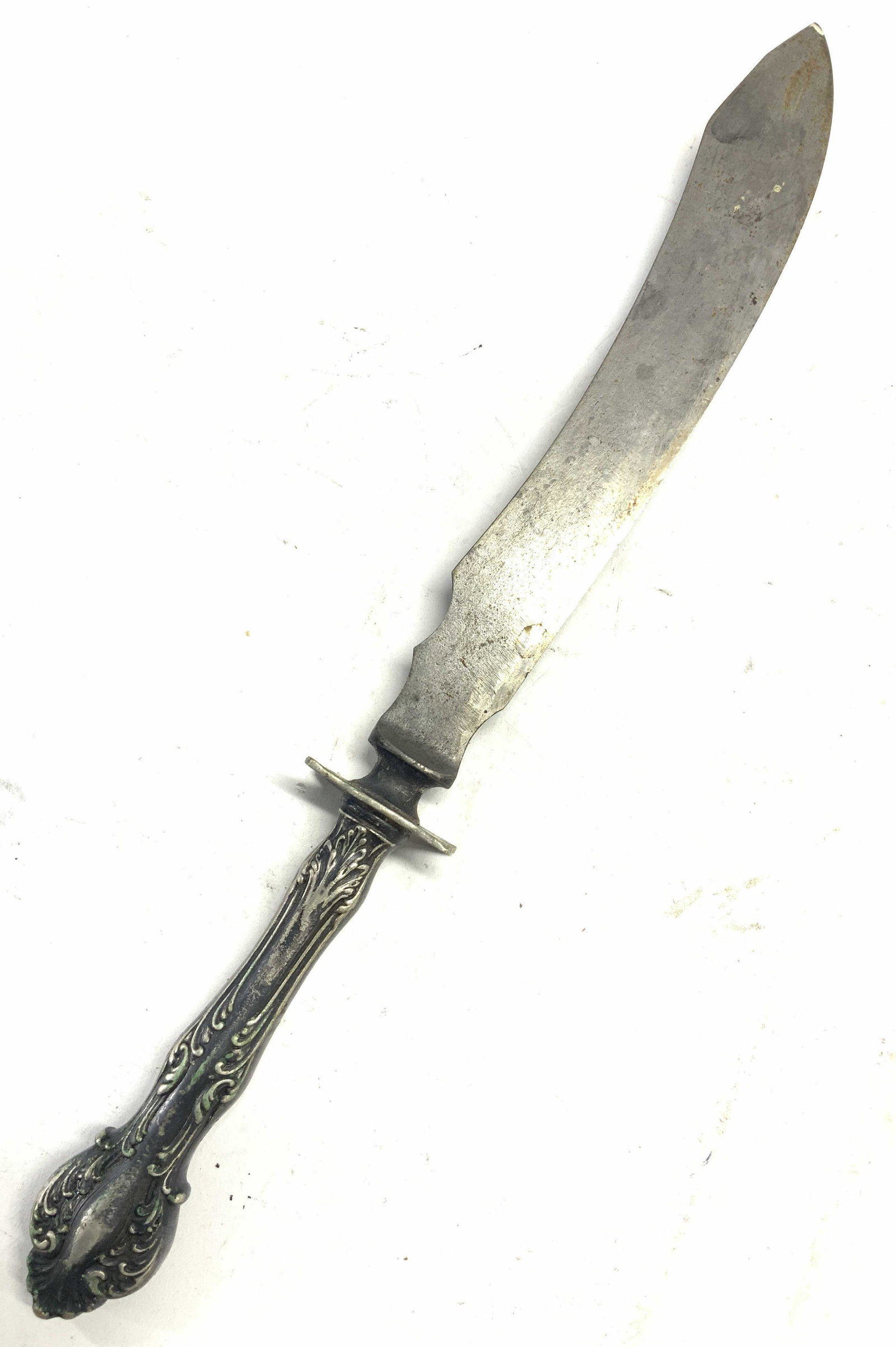Vintage White Metal Carving Knife: A vintage white metal carving knife with a curved blade and handle embossed with floral motifs. Approximately 14 inches total length. Blade is sharp. Condition is consistent with vintage age and use. 