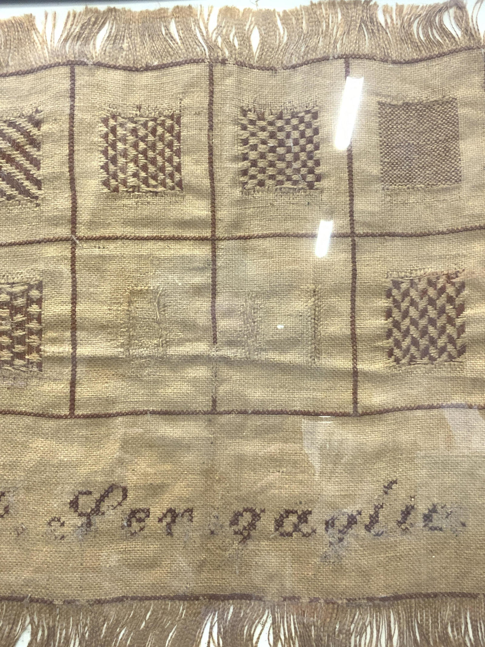 SENIGAGLIA Framed Antique Textile: SENIGAGLIA Framed Antique Textile, beige and brown woven canvas like material with fringe, text is distressed from age, reads ‘Senigaglia’, in frame measures approx 18 x 18 in., black toned metal 