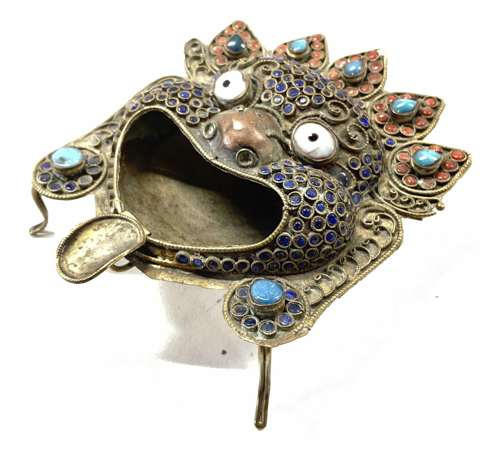 Tibetan Style Small Metal Ashtray: Tibetan Style Small Metal Ashtray. Faceted glass cabochons. Measures approx 4 x 4.5 inches. Face looks like it’s sticking tongue out. Surface wear to piece consistent with age and use. Could be used