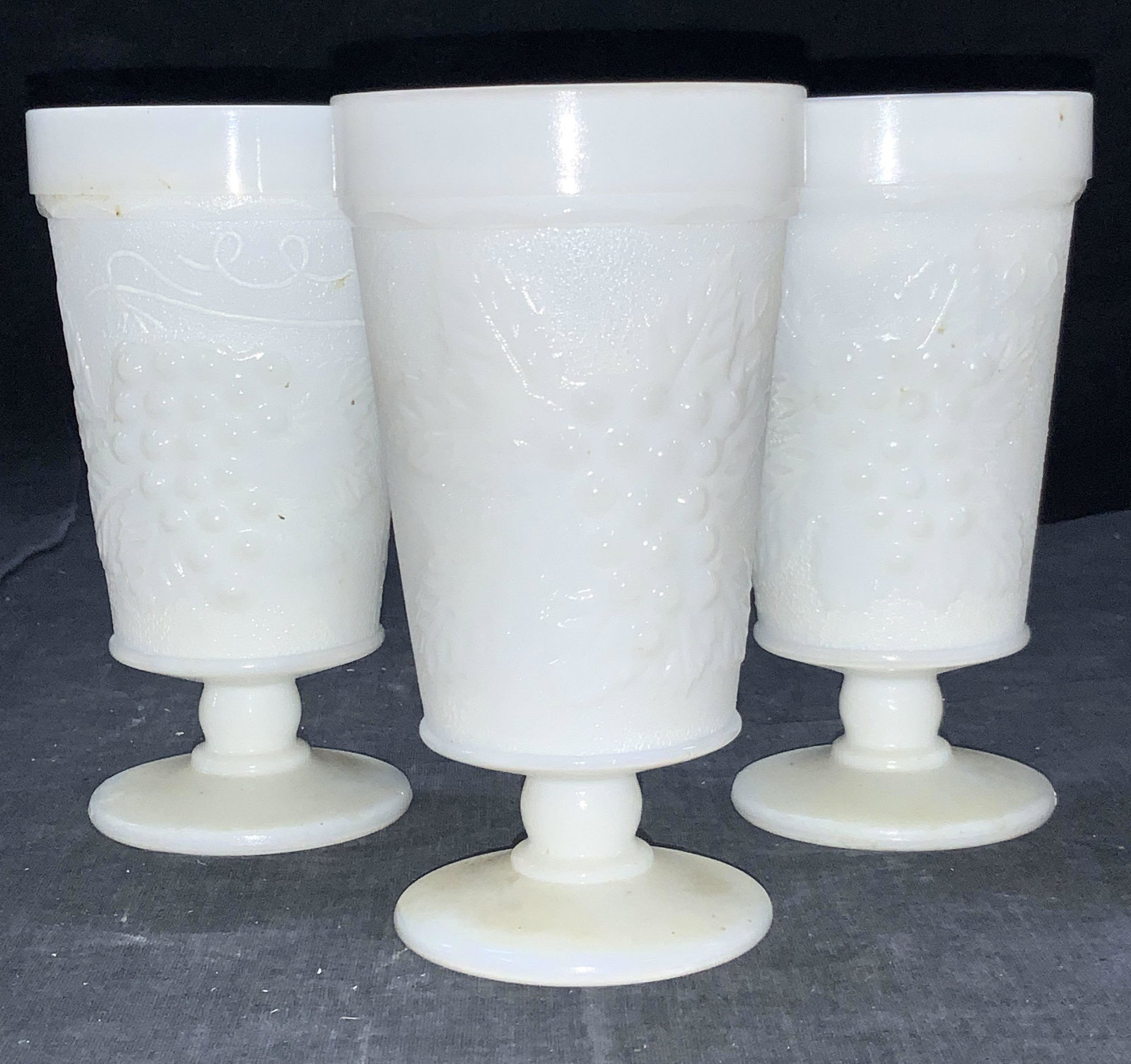 3 Vintage Milk Glass Goblets: 3 vintage Milk Glass footed Goblets with raised motifs of grapes with leaves on exteriors. Approximately 5.5 inches tall. Vintage Milk glass goblets, vintage milk glass, milk glass drink glasses, milk