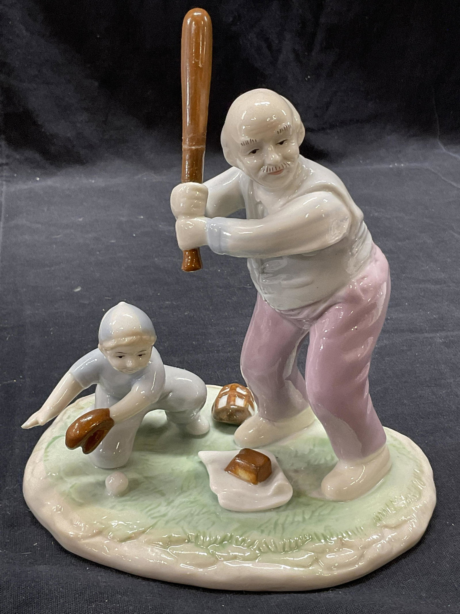 Paul Sebastian Inc Baseball Porcelain Piece, 1992: Porcelain statue of a older gentlemen and child playing baseball. Measure approx 6W x 7H x 4.5D inches. Surface wear to piece consistent with age and use. Ba is damaged and needs repair, refer to fina