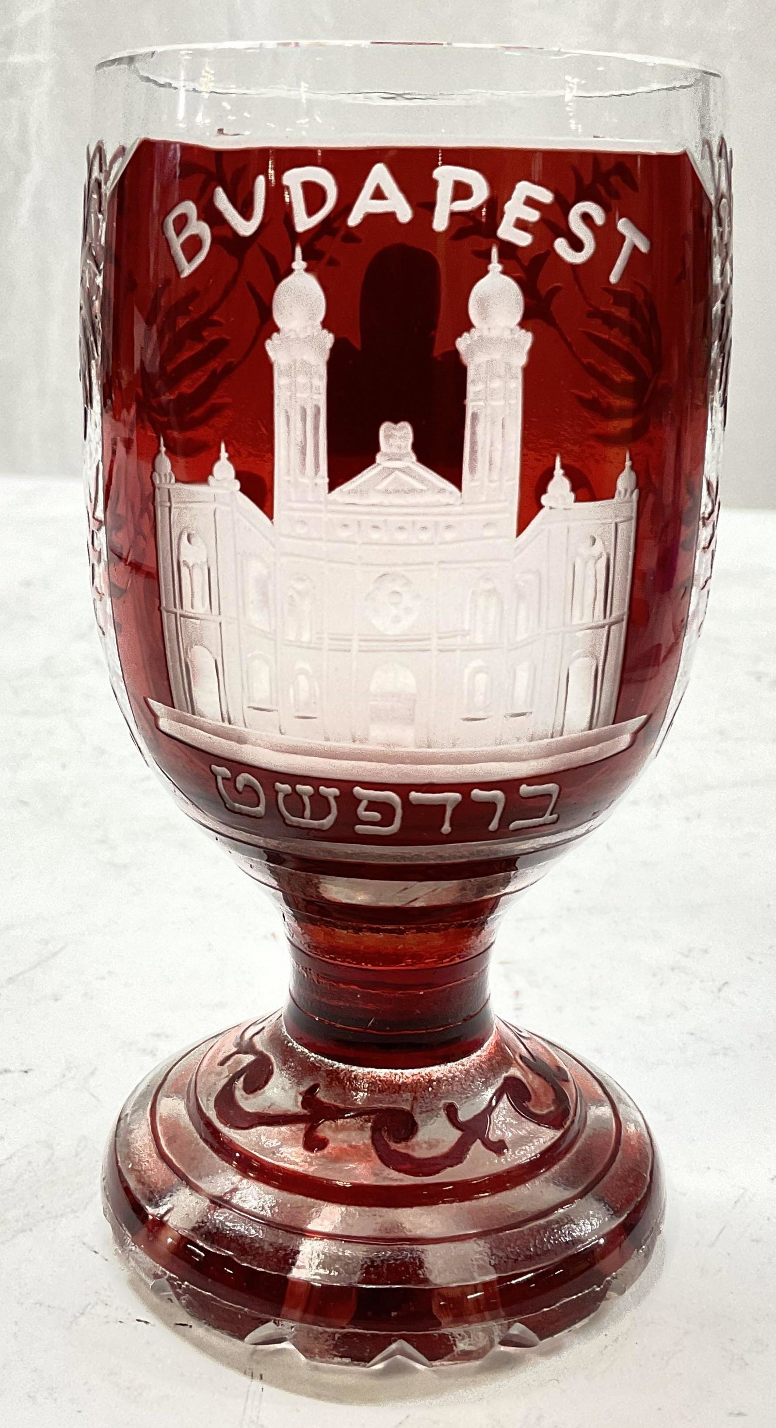 Red Cut Budapest Glass Vessel: Red cut glass. Outside reads Budapest in Hebrew as well. No chips to piece. Minimal surface wear. Measures approx 6 x 3 inches. Budapest, cut glass, read class, Hebrew, art glass, goblet, glass collec