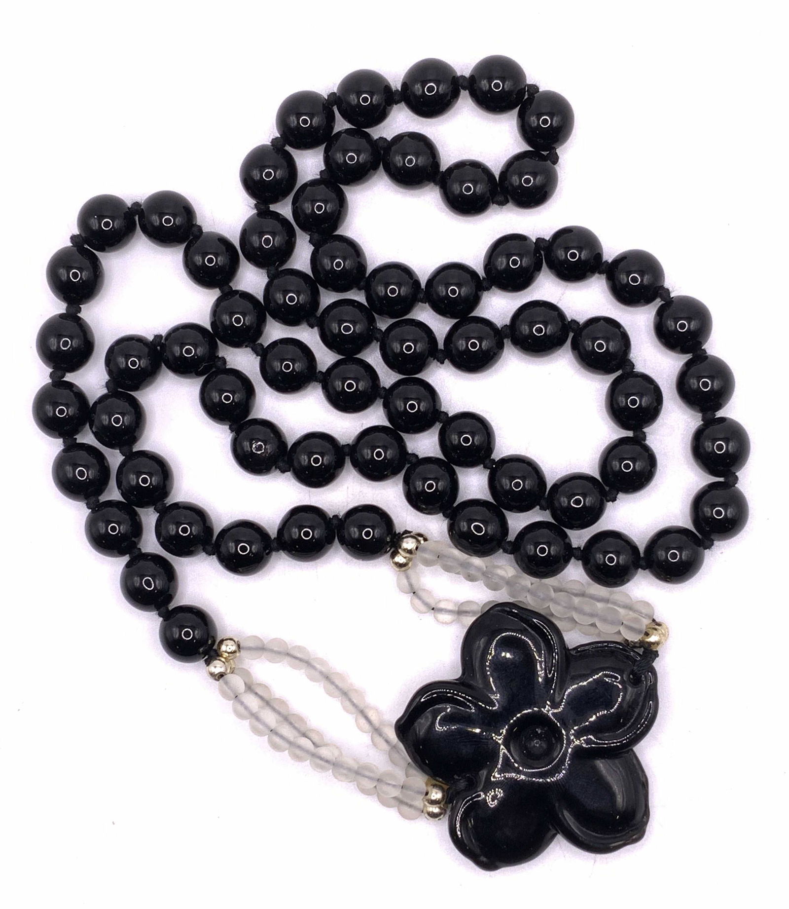 Black Beaded Floral Pendant Necklace: A black beaded floral pendant necklace with frosted white composite beads. Black beads possibly Jasper or onyx. Measures approx. 33 inches long, pendant measures approx. 1.75 inches diameter. Surface