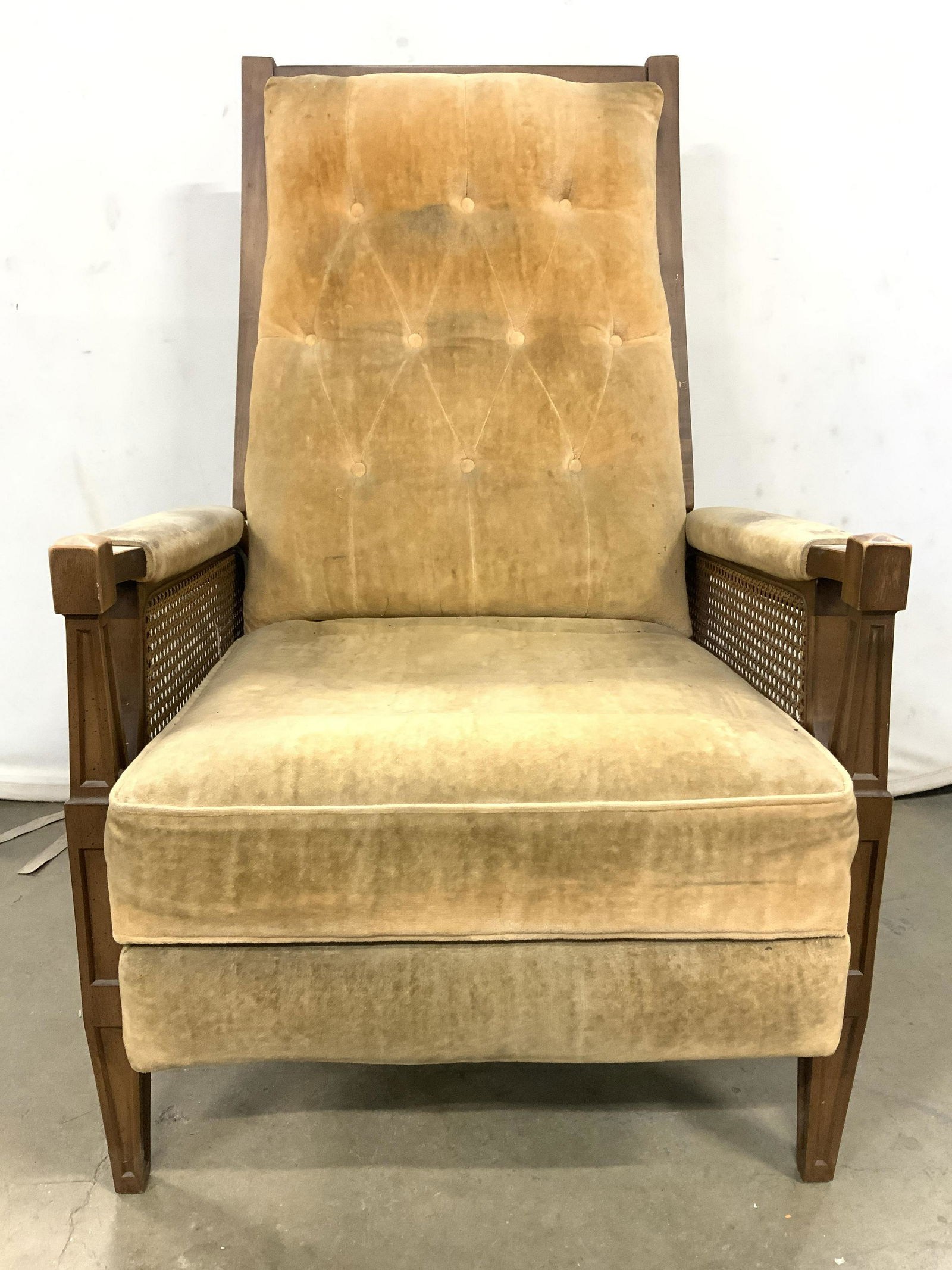 Vintage Upholstered Caned Reclining Armchair: Armchair is vintage possibly antique. Piece has beige toned upholstery, backrest is tufted. Armrests are cushioned. Sides of piece are caned. Piece measures approx 42 inches tall 34 inches deep 26 inc