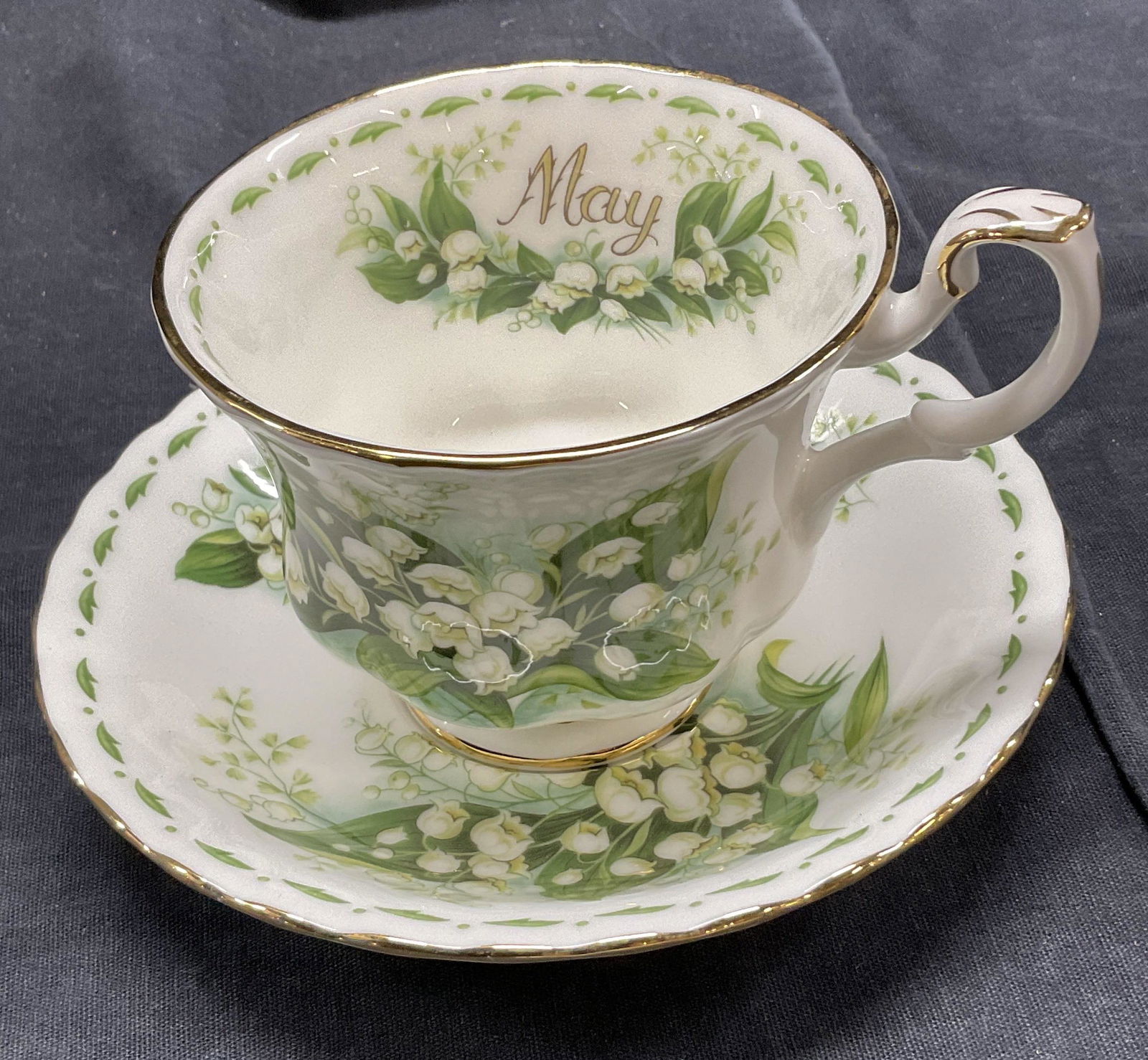 Vintage Royal Albert Bone China Tea Cup & Saucer: 1970 Vintage Royal Albert Bone China Tea Cup & Saucer. Part of the flower of the month series. Lily of the Valley. Gold detail to saucer and tea cup. Reads ‘May ‘ to inner of cup. Measures approx