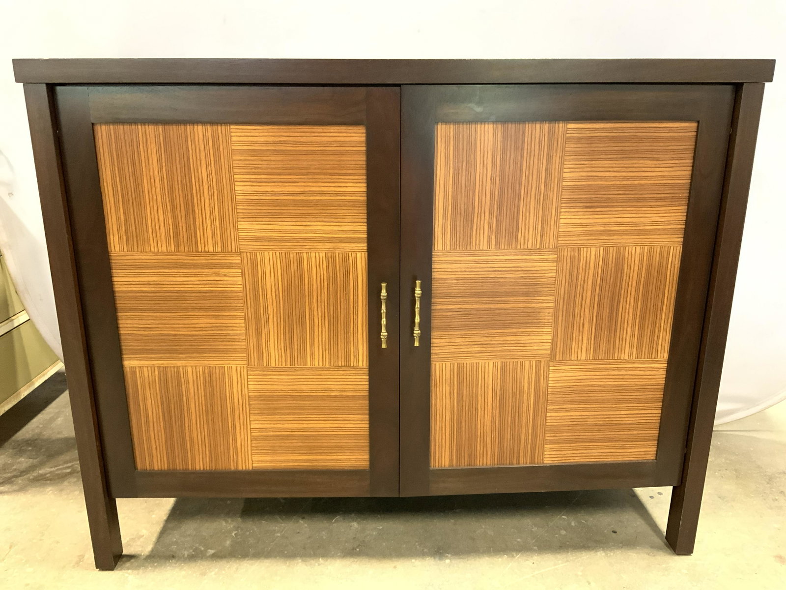 Custom Made 2 Door Mahogany Bar: Bar is brown with beige toned door panels. Piece has gold toned metal handles. Interior includes wine rack and wooden shelves 48.5 inches long 38 inches tall 18.5 inches deep. Mahogany bar, two door b