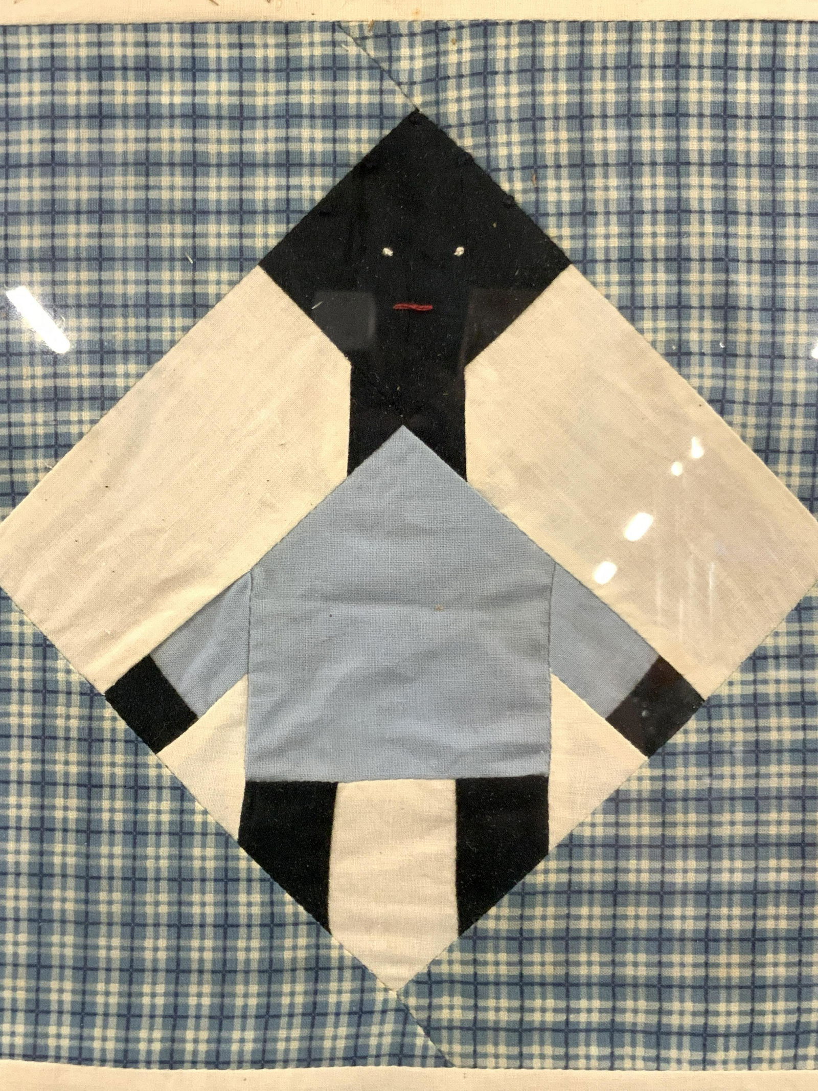 Framed Vintage Patchwork Art: Framed patch work art. Depicting a figure within a white diamond shape created using black and blue fabric. Approximately 13.5 x 13.5 inches, window is approximately 10 x 10 inches. Blue painted woode