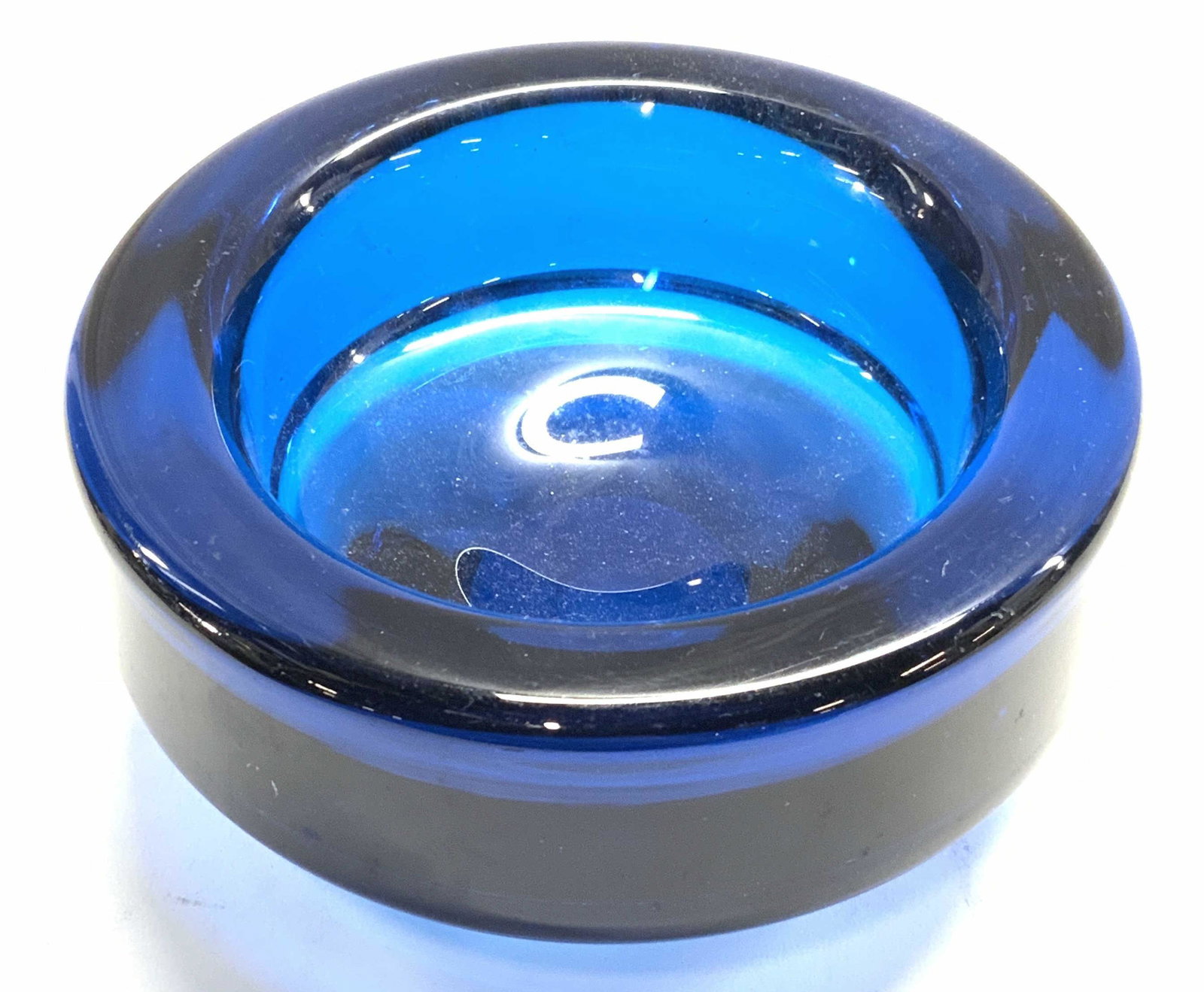 Hand Blown Blue Art Glass Trinket Dish: A hand blown blue art glass trinket dish. Measures approx. 6 inches diameter. Surface wear consistent with use and exposure. Piece is weighted. Glass trinket dish, glass ashtray, trinket dish, art gla