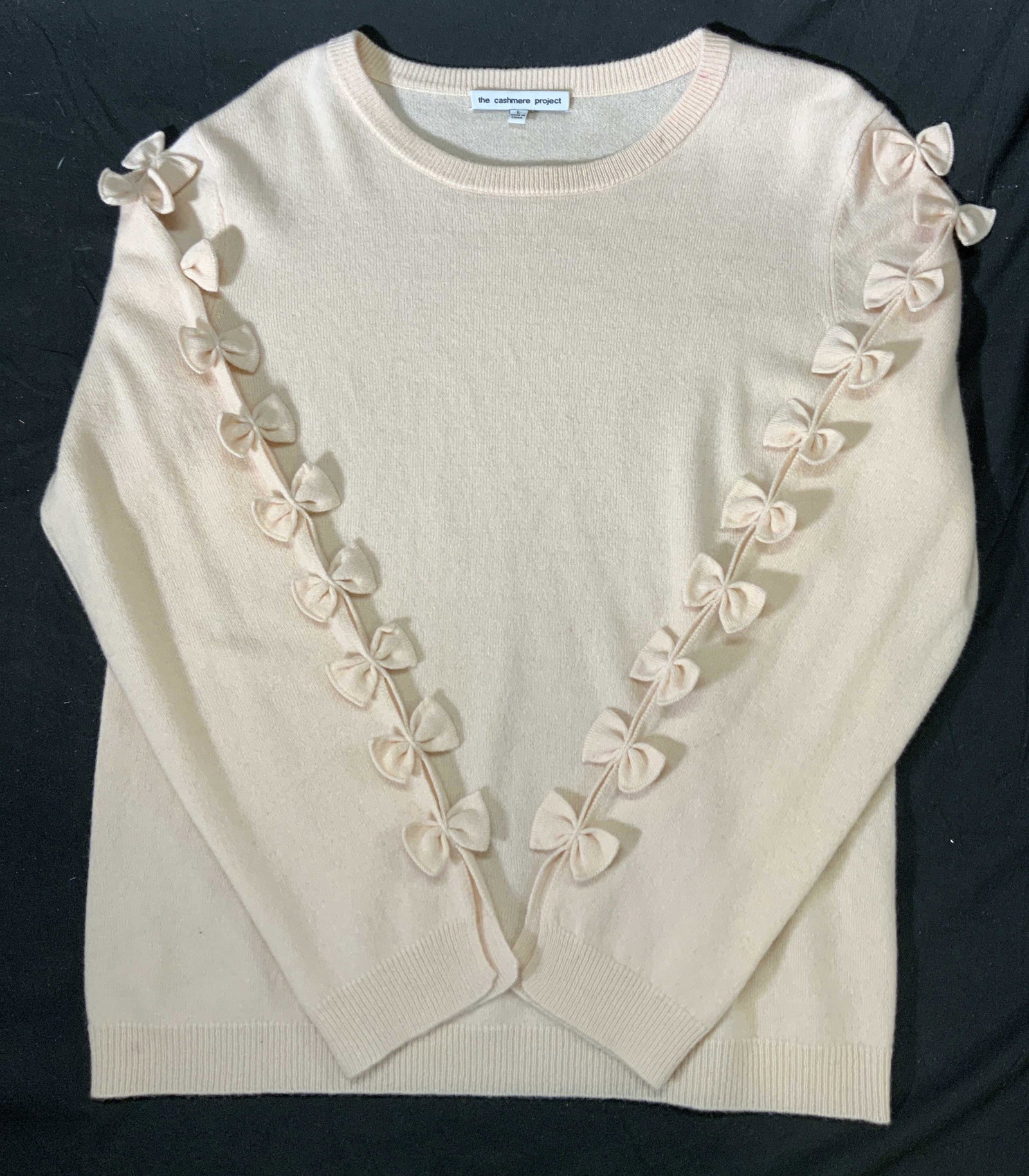 THE CASHMERE PROJECT Light Pink Bow Sweater: The Cashmere Project long sleeve crew neck sweater with bow detail to sleeves in light pink. Size L. 100% cashmere. Some blemishes, small hole to fabric. Property of Manhattan, NY Estate. The cashmere