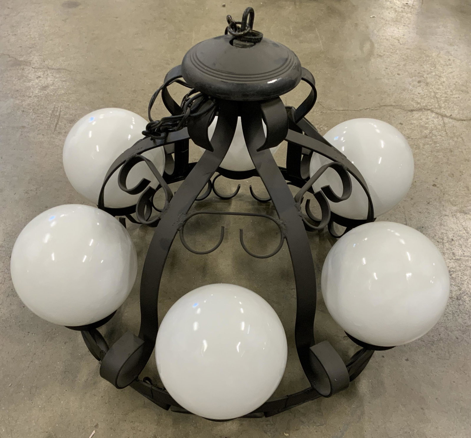 Six Light Black Metal Chandelier W/ Glass Orbs: A six light black metal, possibly wrought iron, chandelier. Curled metalwork. Six glass orb shades. Measures approx 20W x 38 Drop, inches. Chain include in drop length. Some surface wear to piece. Not