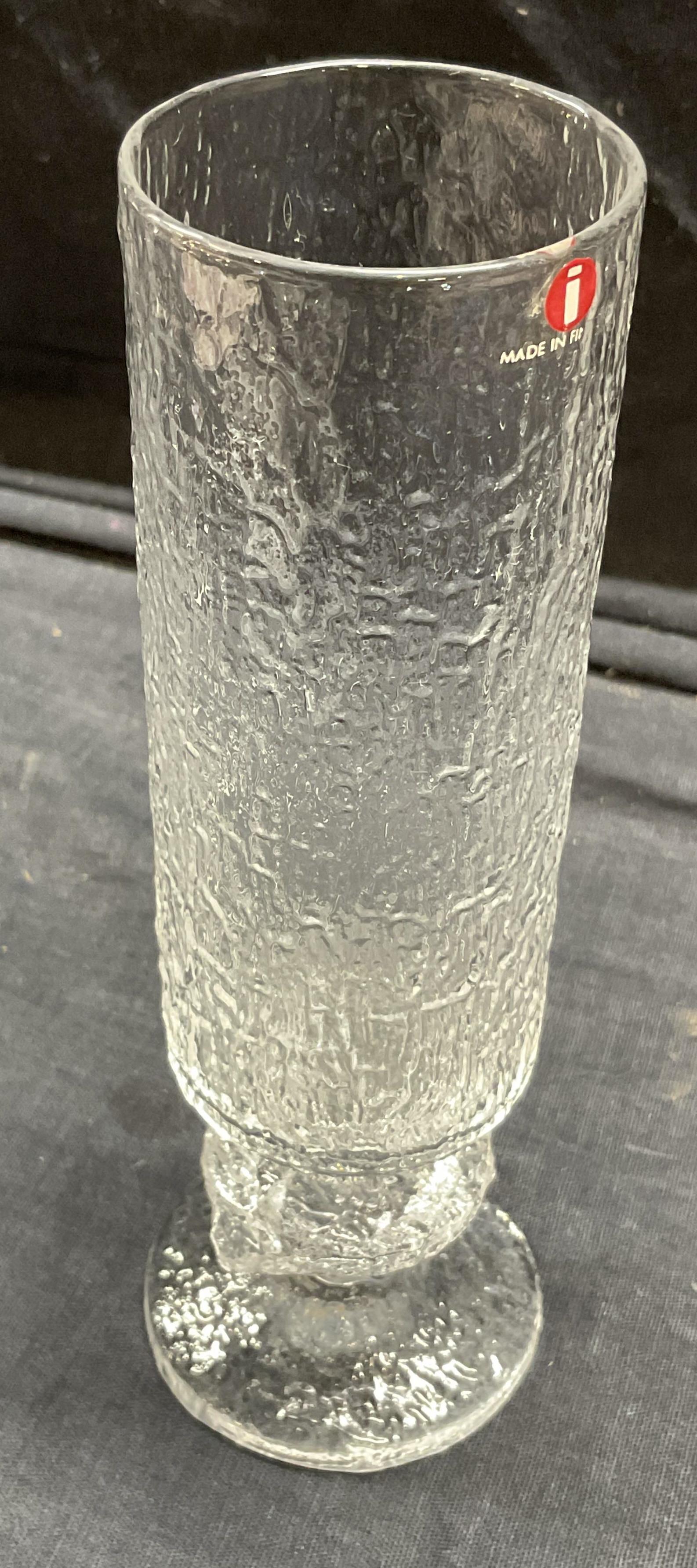 Iiitala Textured Glass Flute, Kitchenware Finland: I symbol label for Iiitala. Textured Glass Flute. Partial Label on glass reads made in Fin, possibly would have been Finland. Measures approx 7 x 2 inches. Surface wear to piece consistent with age an
