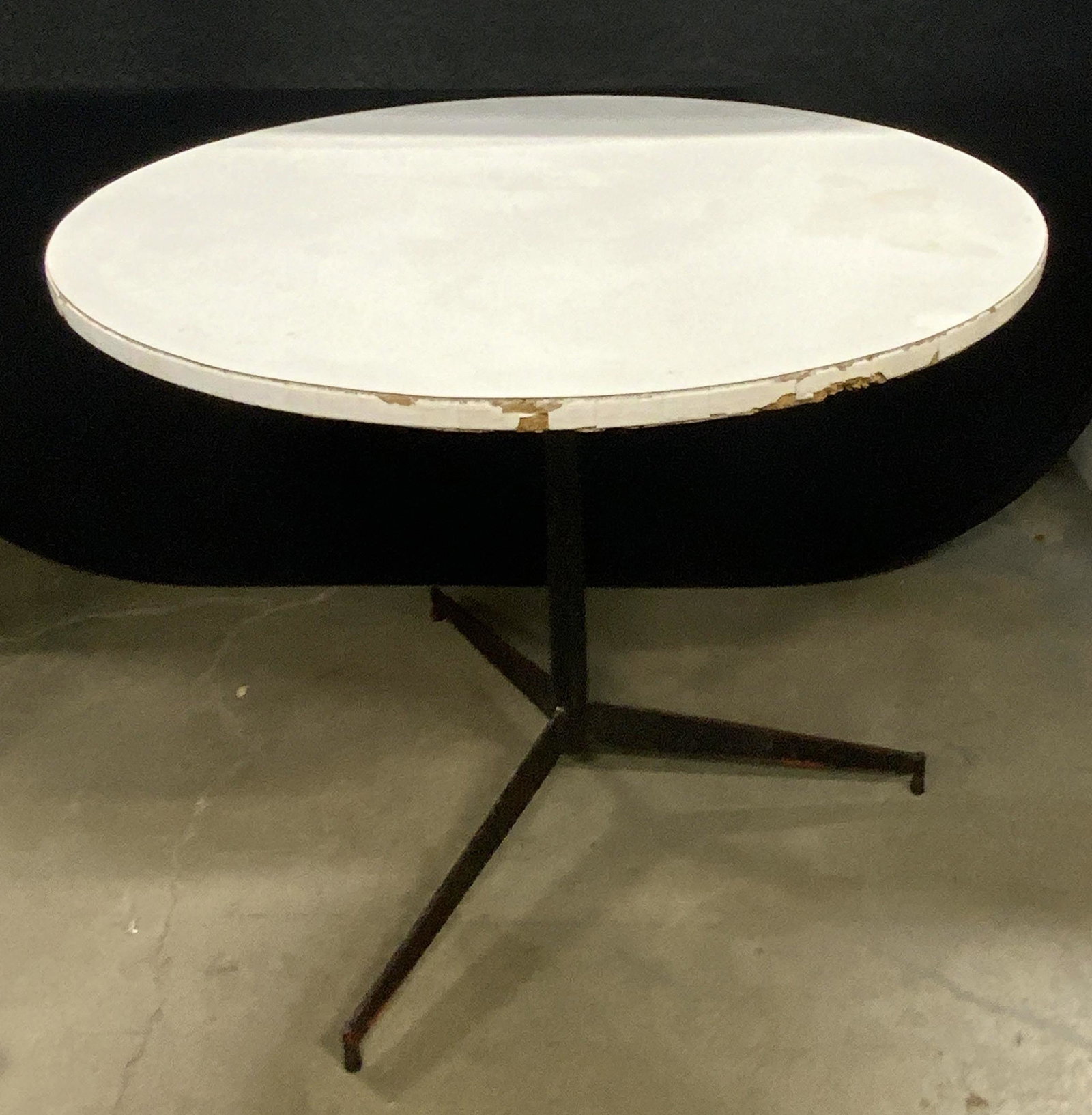 White Circular Kitchen Table: White hued pressboard table. White rectangular tiles along the rim. Measures approx 29H x 36W in. Evident wear to piece. Discoloration, losses, chipping. Black pedestal base. Circular White Kitchen Ta