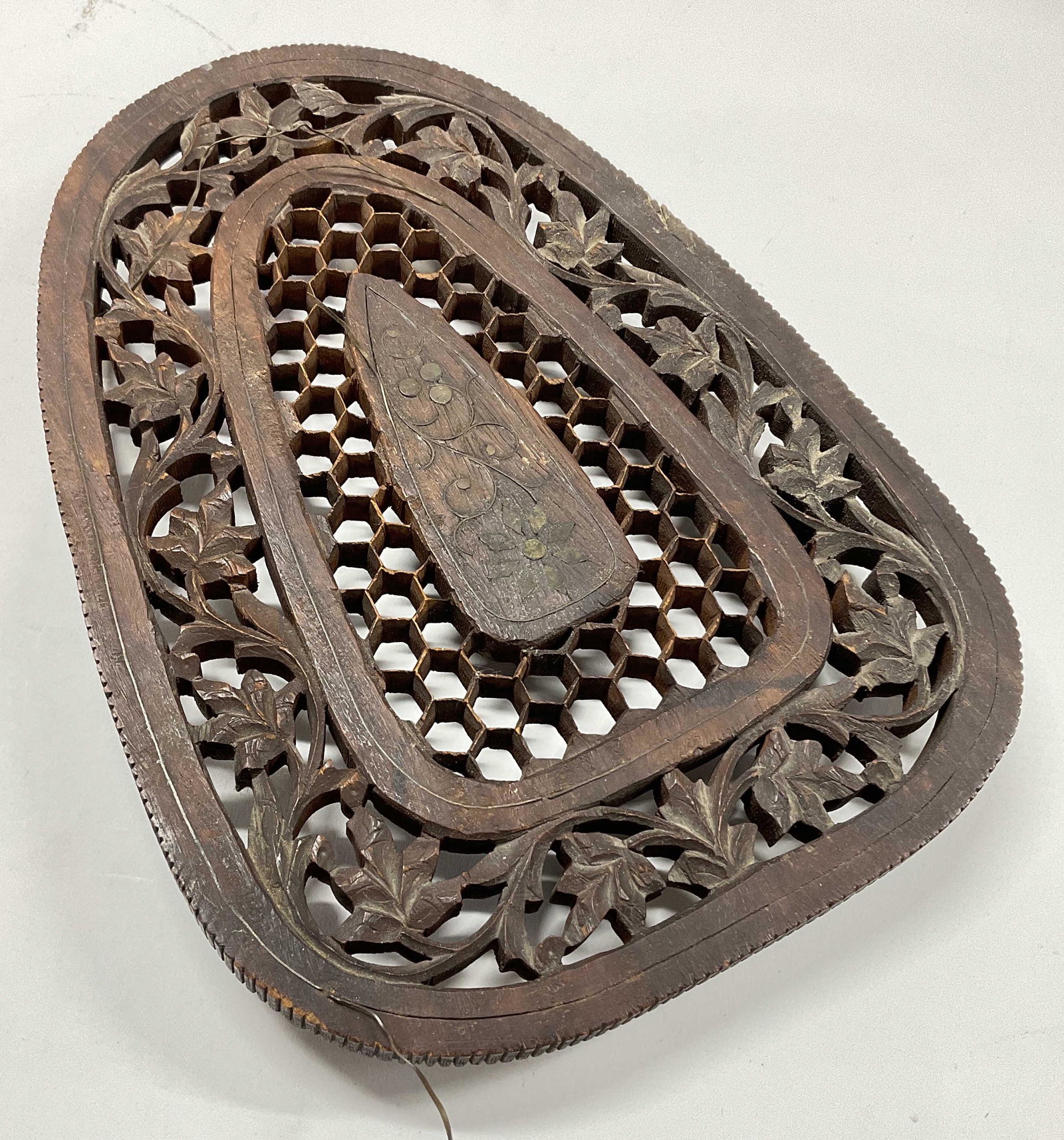 Black Forest Carved Trivet W Metal Inlay: Black Forest Carved Trivet W Metal Inlay and wooden feet. Honey comb detail white filigree to piece. Some Metal inlay not in piece and is somewhat coming out of piece. Measures approx 11 x 8 inches. S