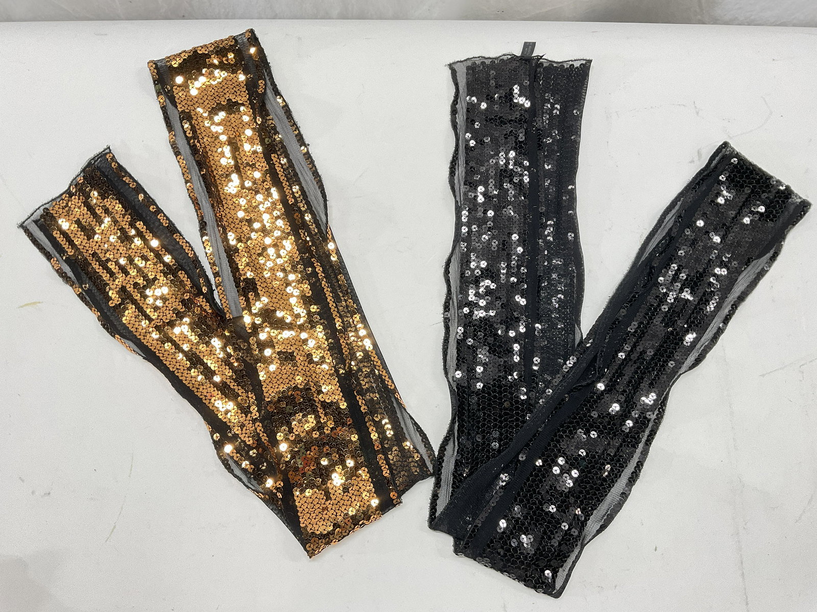 Lot 2 Sequined Fashion Accessories: Lot 2 Sequined Neck Accessories. Measures approx 64 inches in length. One is black with black sequins, material tag reads, nylon & polyester. The 2nd is black with bronze tone sequins. Material is nyl