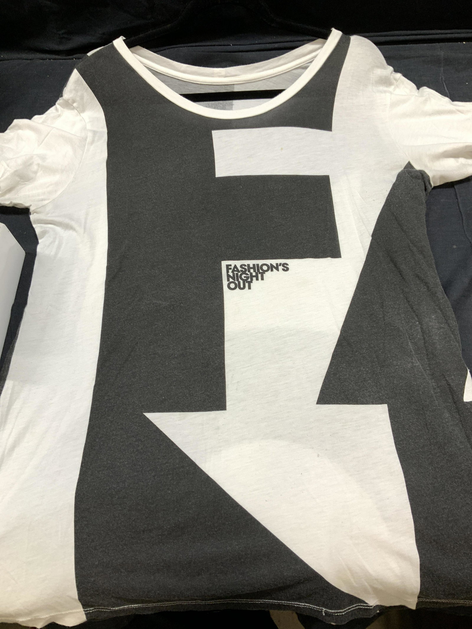 Fashions Night Out Color Block Tee Shirt: White cotton/ modal short sleeve tee shirt, reads Fashion’s Night Out’ in a white and black abstract color block pattern. size large, should fit x large. Wide scoop neck. Light spots here and ther