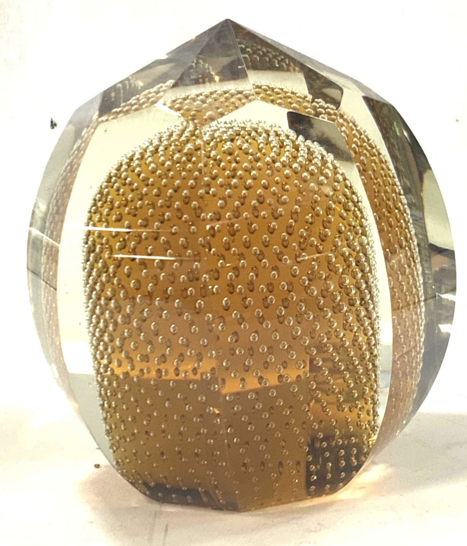 Vintage Amber Toned Geometric Glass Paperweight: A vintage glass paperweight, layered with clear glass exterior in geometric cuts with interior amber tone with intricate bubble placement. Approximately 5 inches tall. Vintage paperweight, glass paper