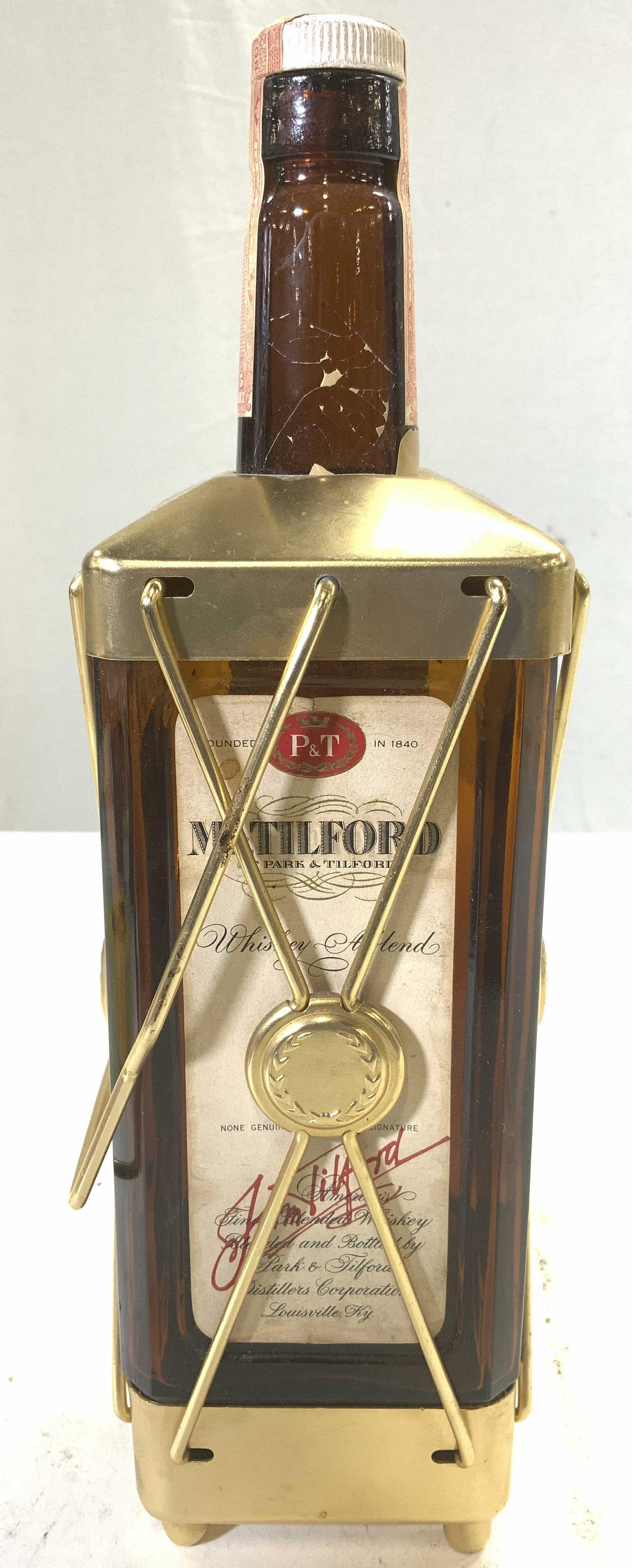 PARK & TILFORD Whiskey Liquor Bottle Music Box: Bottle reads PARK & TILFORD. Piece is glass and metal with swinging handle. Underside reads SWISS HARMONY INC. Underside has wind which plays music. Piece measures approx 11.5 inches tall 3.5 inches w