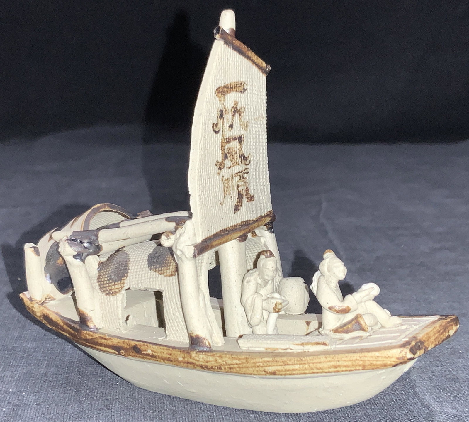Vintage Asian Ceramic House Boat Ornament: Vintage ceramic made tabletop ornament of two people on a house boat, made from raw clay with minor glazing to create accents. Asian characters painting on the sail of the boat. Approximately 4 inches