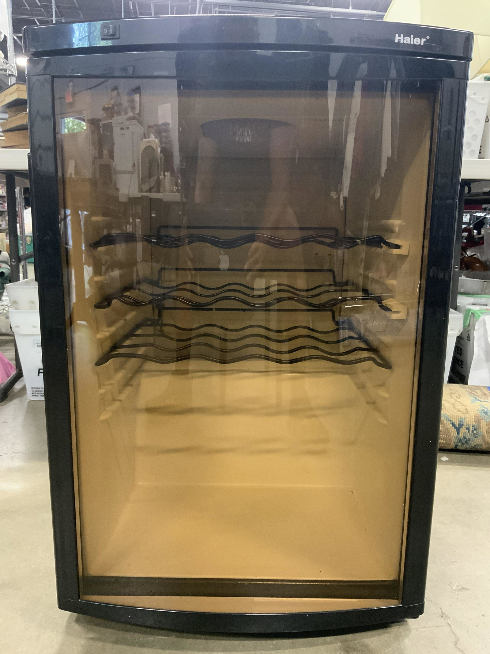 HAIER Three Rack Wine Cooler: Wine cooler has black toned exterior. Piece has 3 metal racks inside. Interior is white toned. Cooler has front glass window. Piece measures approx 31 inches tall 20 inches wide 21 inches deep. Wine c