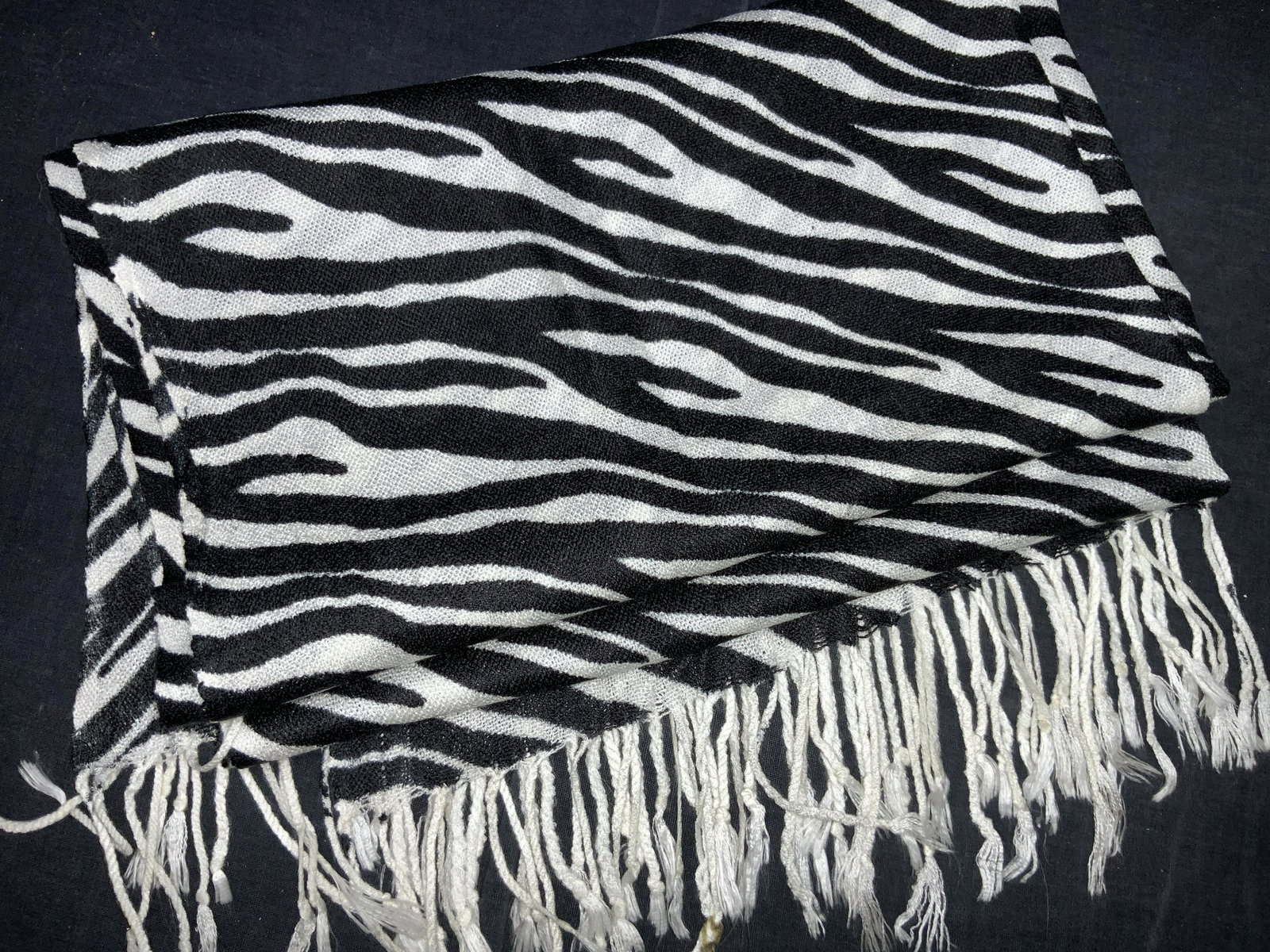 100% Pashmina Zebra Print Scarf: Black and white zebra print fringe scarf with material tag reading Pashmina, 100% Pashmina. Approximately 60 inches long and 22 inches wide. Evident staining to fringe. Pashmina scarf, zebra print sca