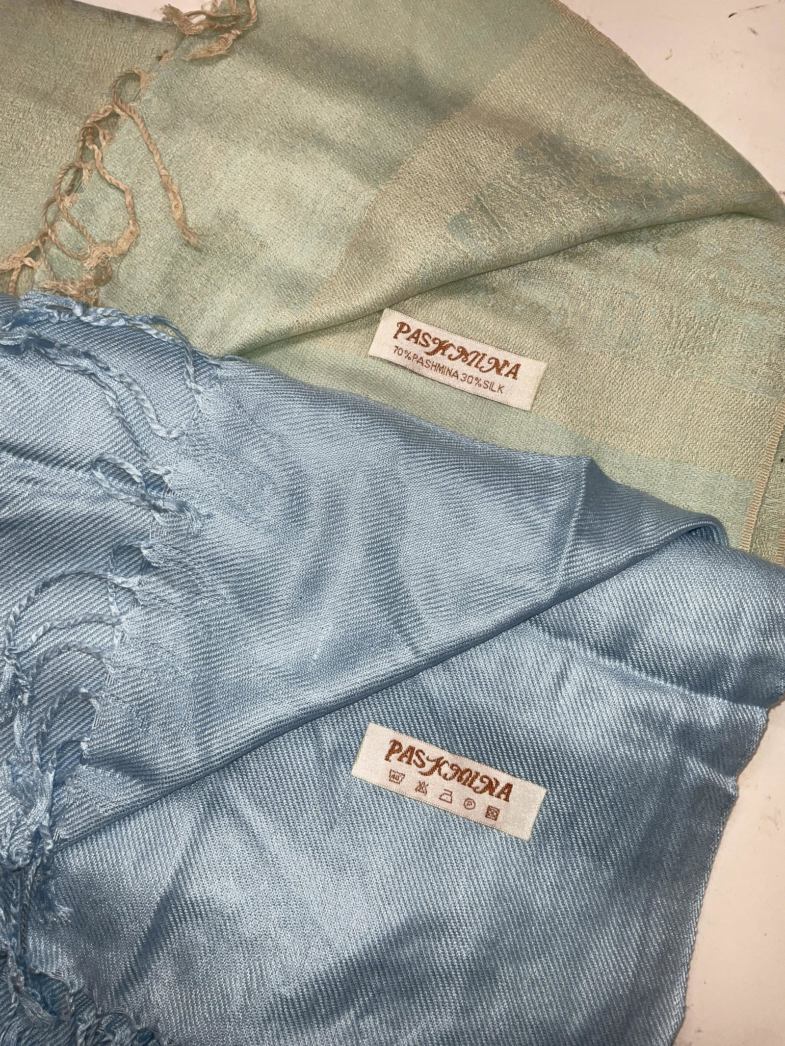 Lot 2 PASHMINA Scarves W Fringes: 2 PASHMINA Scarves W Fringes. Sea foam Green with some Damask detail to scarf and a plain sky blue scarf. Measures approx 70 inches in length. Minor stain and pulling of thread to pieces. Made of pash