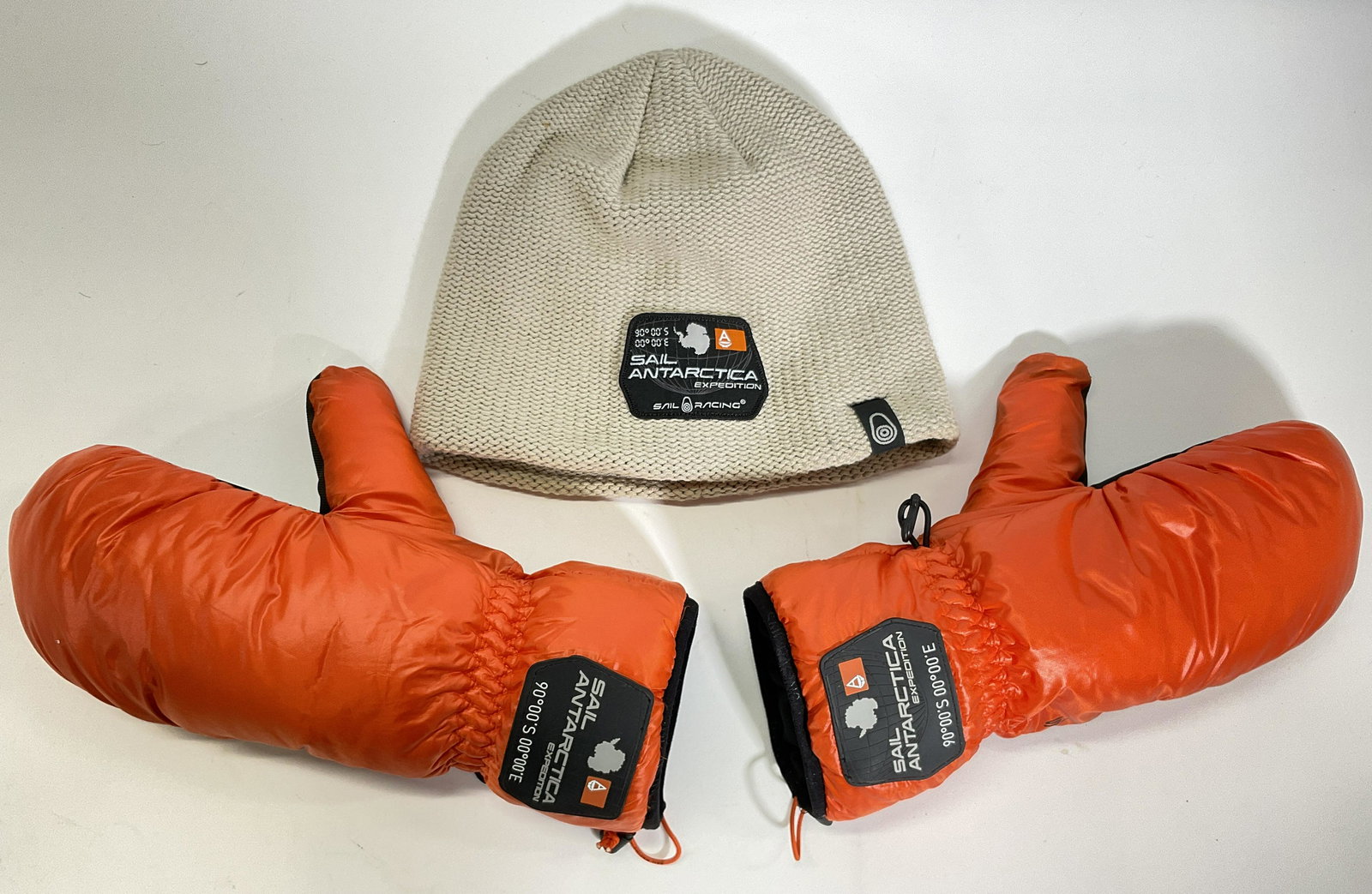 SAIL RACING Gear, Antarctica Expedition: Lot of Sail Racing Knit hat and pair of snow gloves. Pieces are labeled with Sail Antarctica Expedition on outer part. Hat is 60% cotton. Gloves on inside read M with white goose down. Winter gear hav