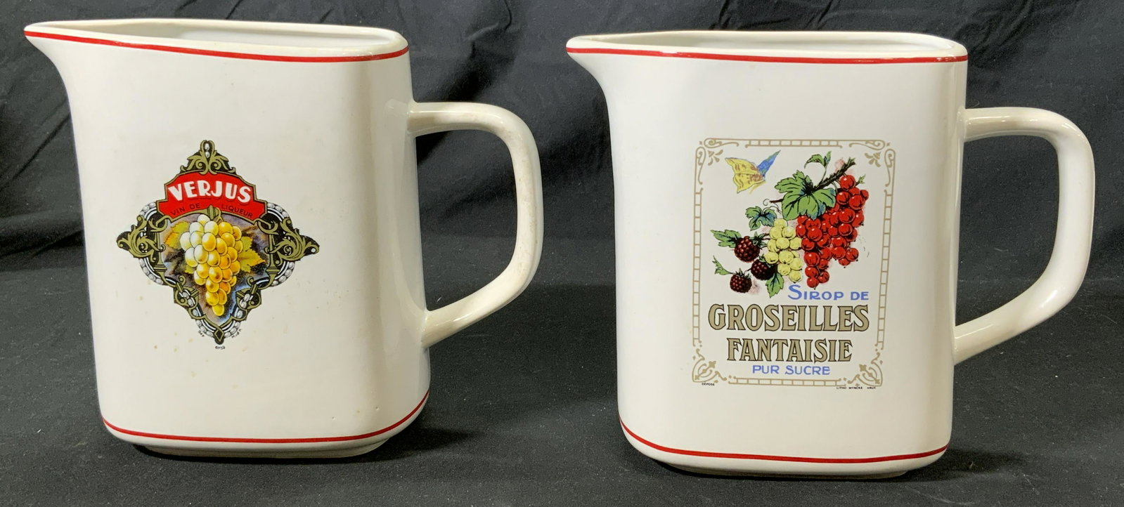 Pr KISS THAT FROG Vintage Ceramic Pitchers Turkey: Pair of vintage Kiss That Frog ceramic pitchers in white with graphic grape and wine motifs. Some wear to surface consistent with age and exposure. Trademarked to undersides. Each measures approx. 6 x