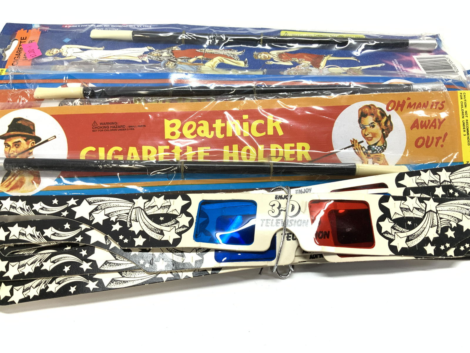 Lot 7 Beatnick Cigarette Holders, NIP , more: Flapper Style long cigarette holders , new in packages, measure 11.75 in. Long. Additional lot 16 vintage paper 3D glasses with the red and blue cellophane lenses, typical of the 1970s - 1990s. 16 in.