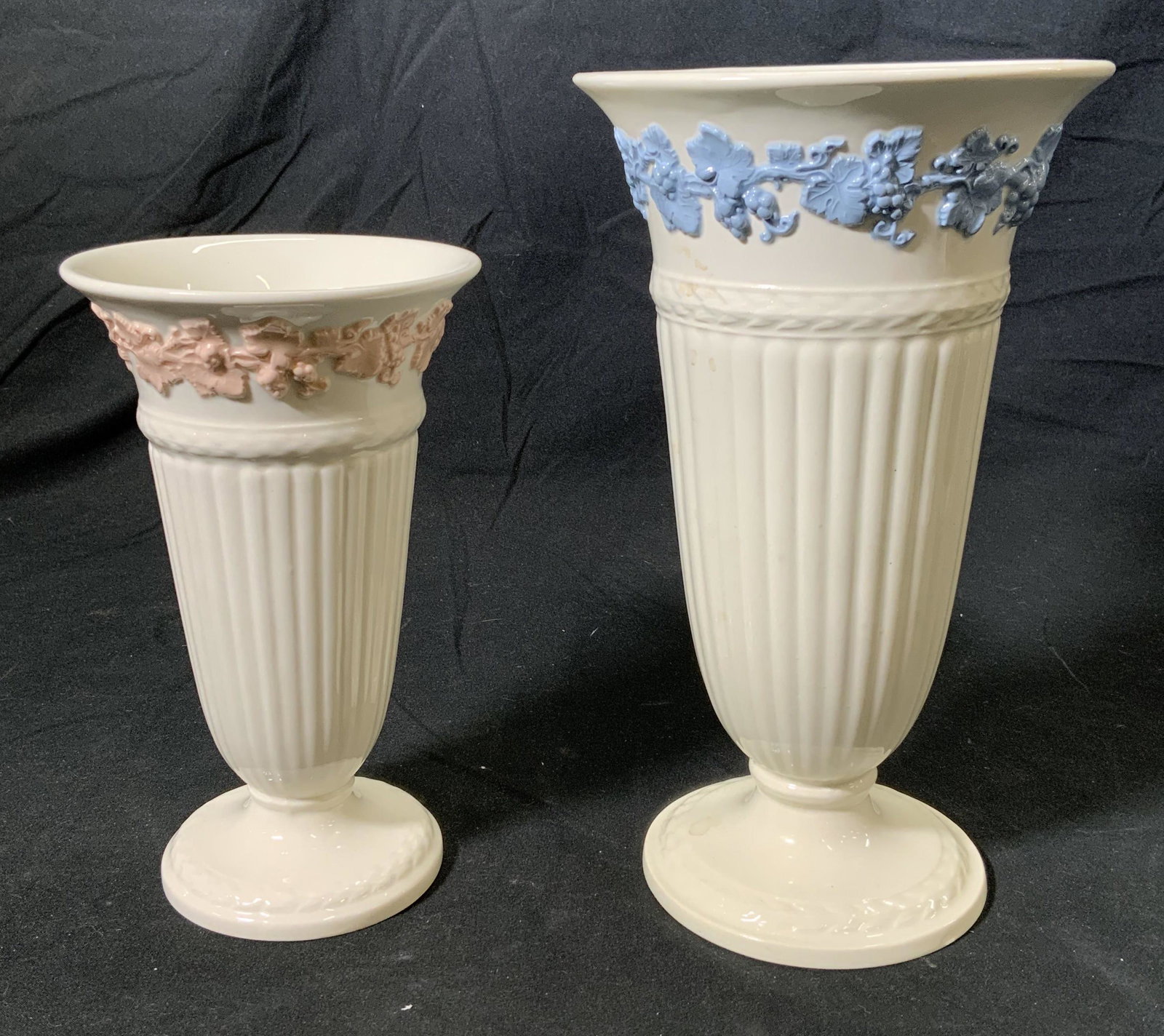 Lot2 WEDGWOOD Queens Ware Vases, England: 1 pink and white Wedgwood Queens Ware vase with grape motif, measures approx. 4 diameter x 6.5 inches tall. 1 blue and white Wedgwood Queens Ware vase with grape motif, measures approx. 5 diameter x 8
