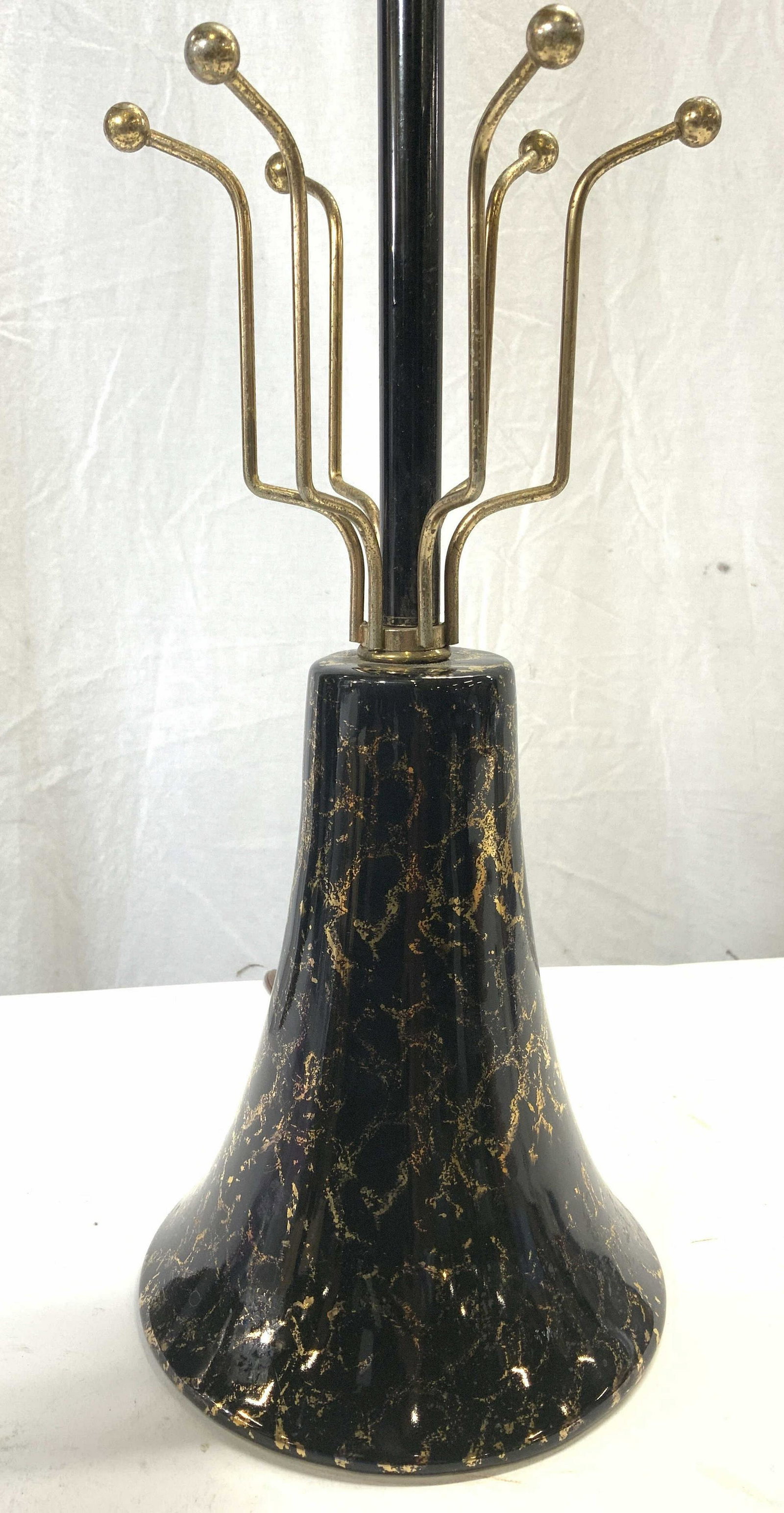 Porcelain Base Lamp W Metal Spokes: Lamp has porcelain base. Mid piece has gold toned metal spokes which appears to be where a shade would rest. Lamp includes harp and finial. Base of lamp has bell shape. Piece measures approx 21 inches
