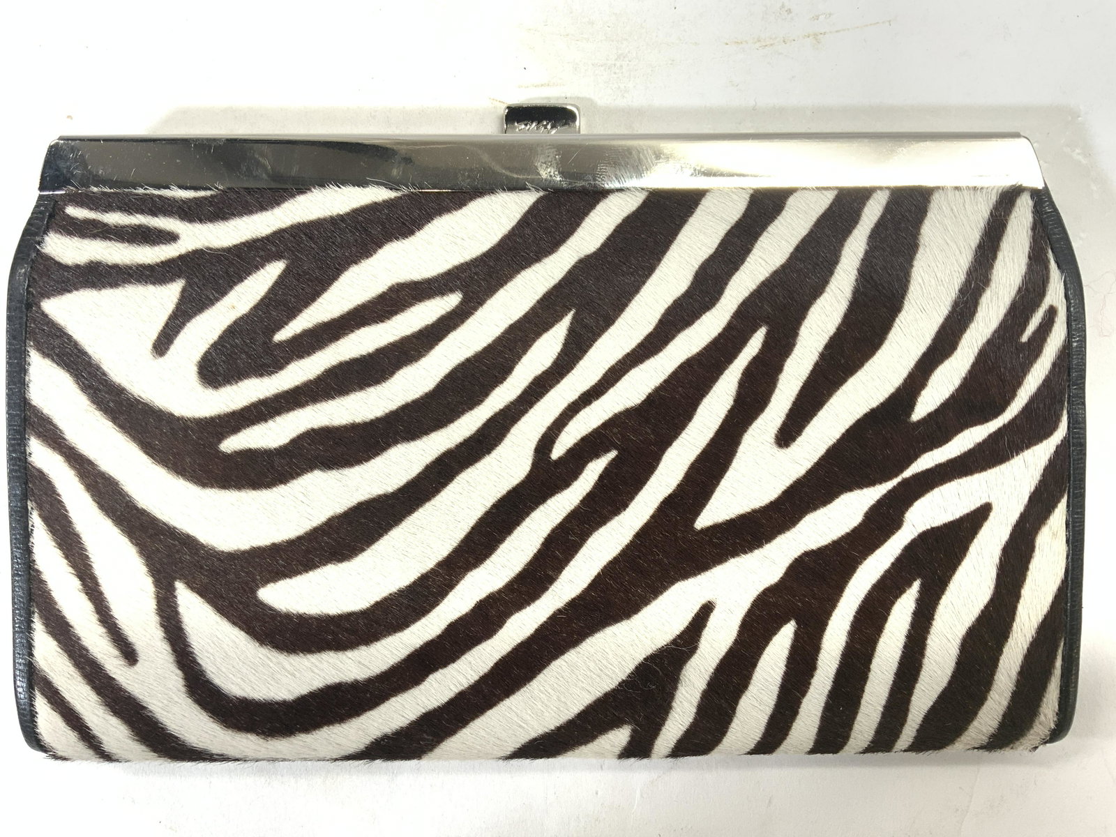 ABAS Zebra Print Clutch: Clasp reads ABAS. Exterior has Zebra print. Interior has 5 accordion pocket areas 1 of which is zippered. Piece measures approx 7.5 inches long 5 inches tall. Clutch, ABAS clutch, zebra print clutch, 