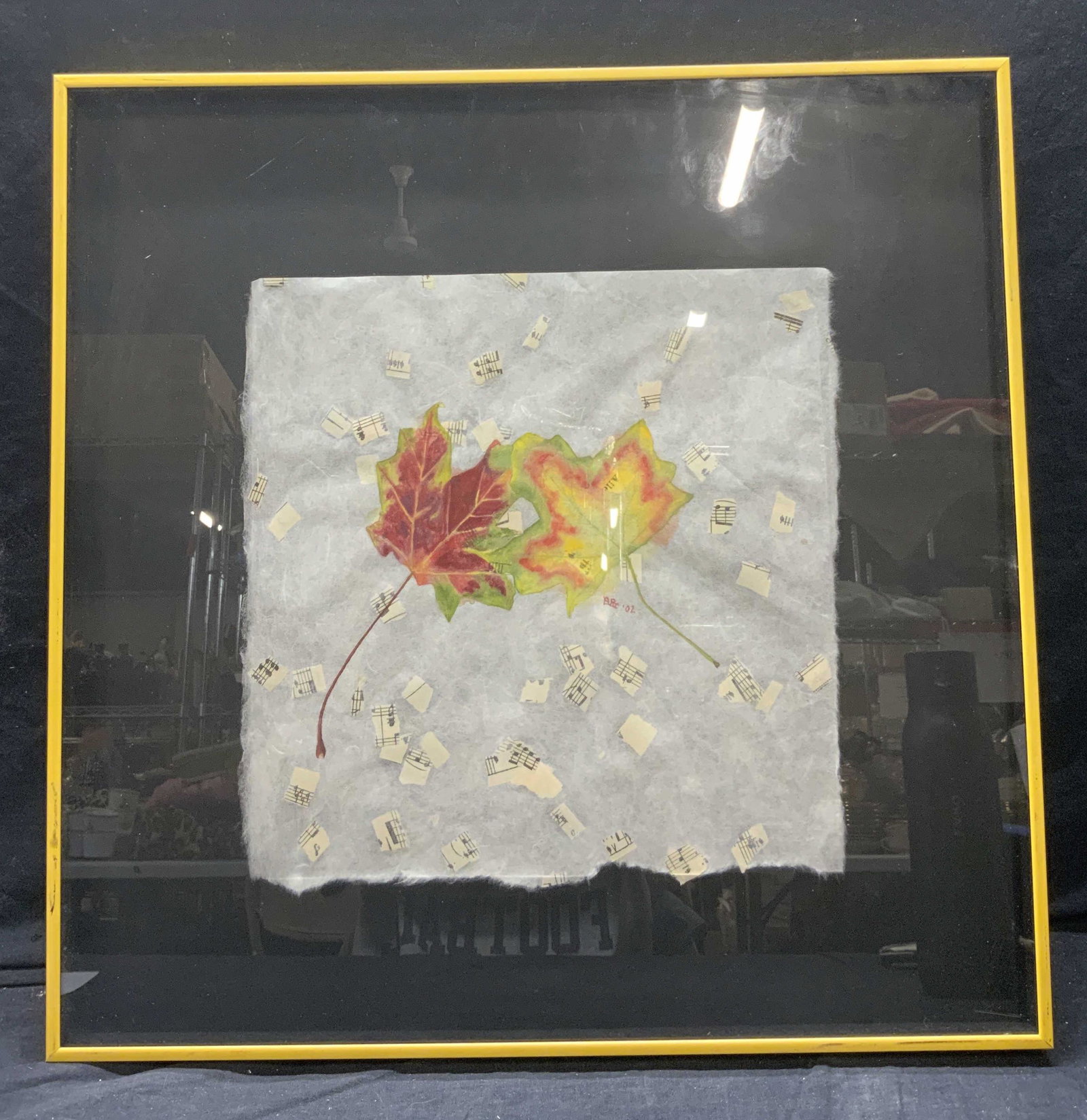 Signed Mixed Media Art Piece: Signed Mixed Media Art Piece, signed near the center Art 02, subject shows pieces of a music sheet with autumn leaves against a fuzzy gray background. In frame measures approx 20 1/4 x 20 1/4 in., yel