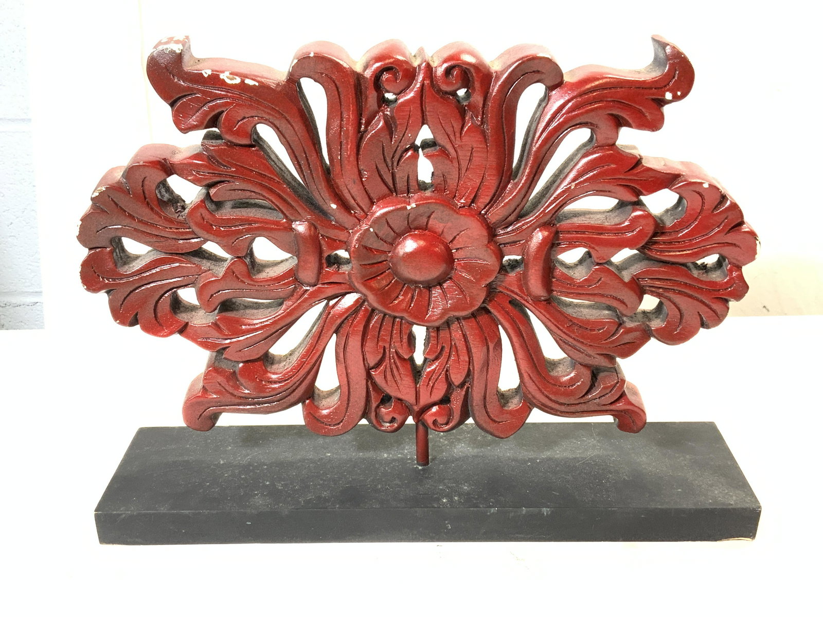 Asian Floral Carved Wood Centerpiece: Asian floral motif carved wood centerpiece in maroon with black base. Surface wear consistent with age and exposure. Made in Thailand. Measures approx. 15.75 x 3.75 x 11 inches. Table decor, Asian dec