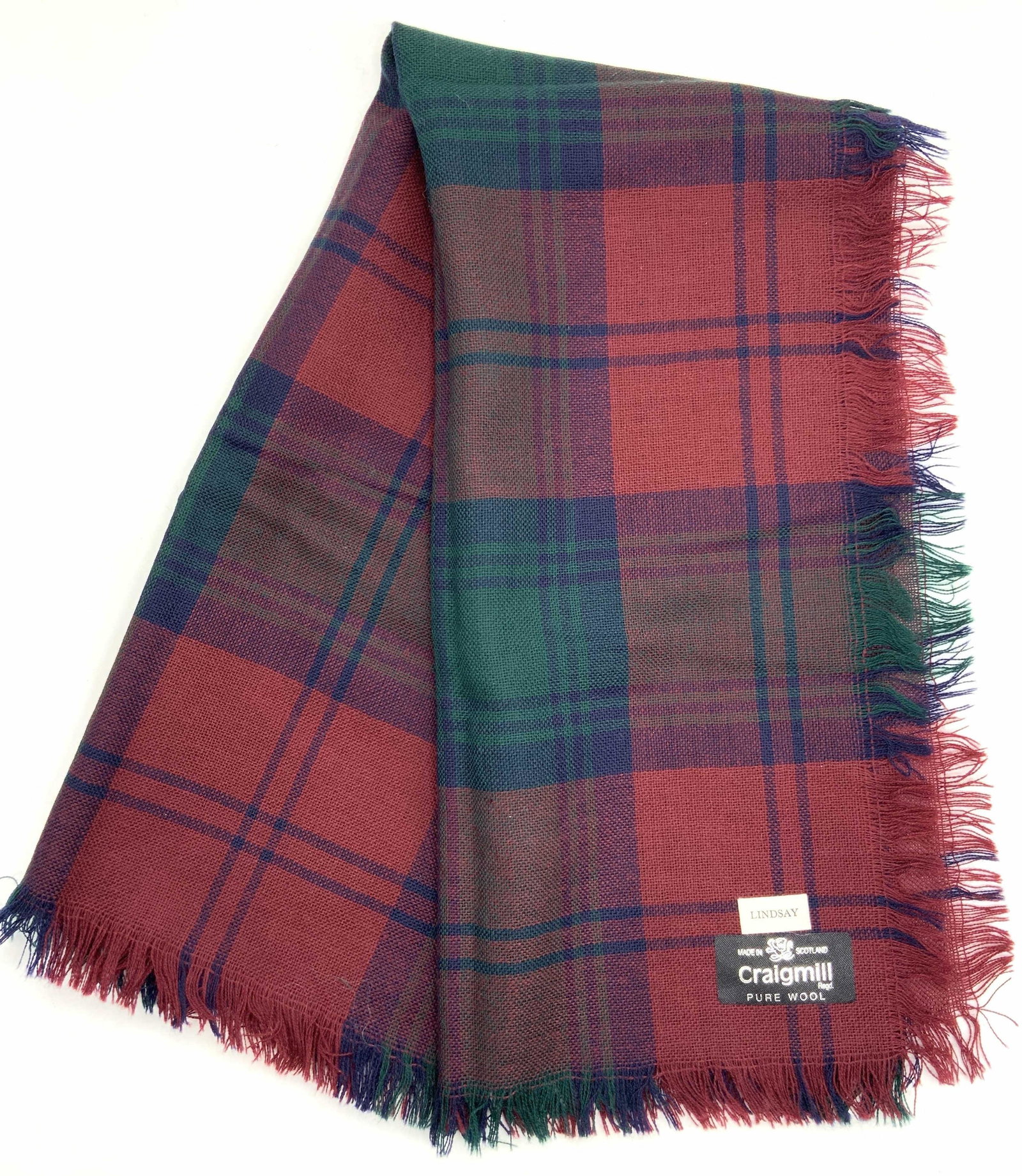 CRAIGMILL Wool Plaid Scarf, Scotland: Plaid scarf in tones of red, blue and green. Marked on tag CRAIGMILL pure wool made in Scotland. Name tag scarf reads Lindsay. Approximately 30 x 30 inches. Evident holes in Fabric. CRAIGMILL pure woo