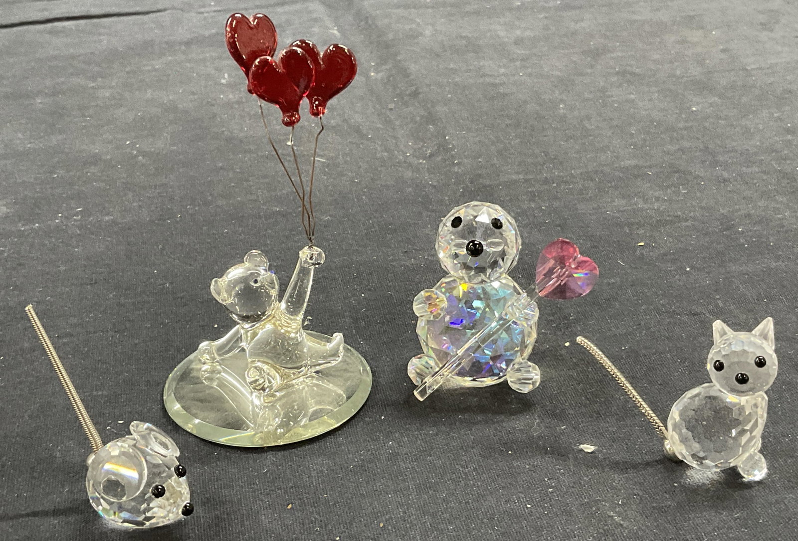 Lot 4 Glass Animal Tabletop Figurals: Lot 4 Glass Animal Tabletop Figurals. Largest measures approx. 3.5 x 2 inches. Mouse, cat with a minor chip to ear, a seal figure with a heart wand and a glass bear holding heart balloons. Prior repai