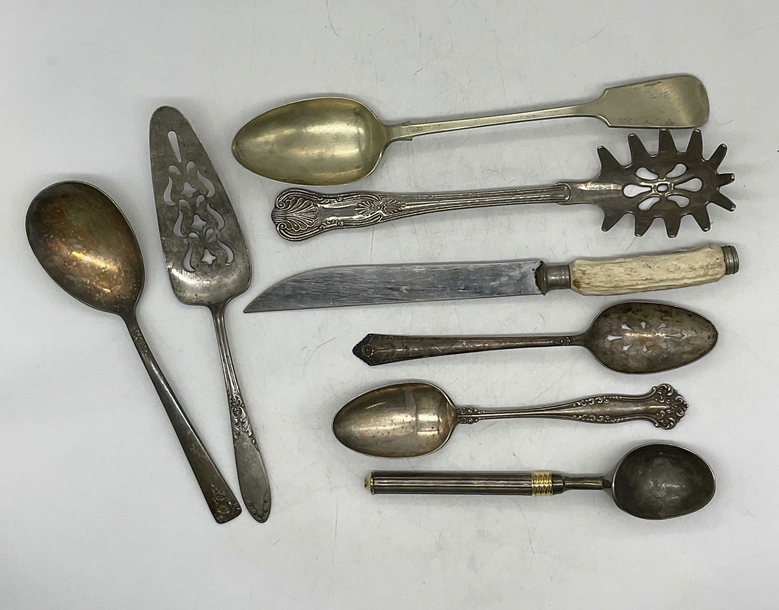 Lot 8 Sterling Utensils & More: Lot 8 silverware serving utensils. 2 tested positive for silver, weight is 5.02 OZT. Carving knife has a faux antler handle. Others detailed with floral decor. Surface wear to pieces consisted with ag