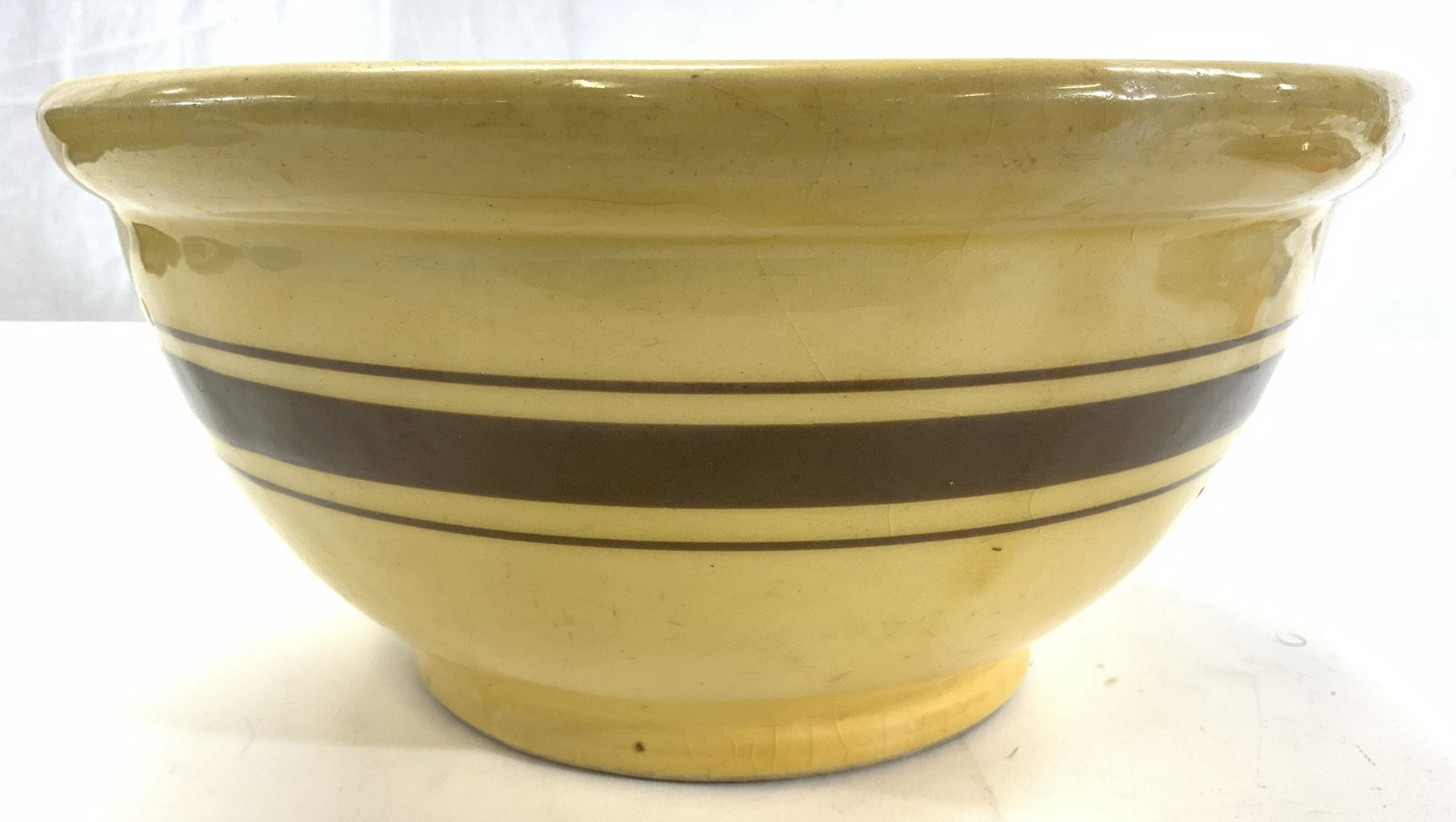 Vintage Yellow Ware Ceramic Bowl: Underside is inscribed USA 120. Bowl is vintage possibly antique. Piece appears to be ceramic. Bowl is yellow with brown toned stripe detail. Piece measures approx 10.25 inches diameter 5 inches tall.