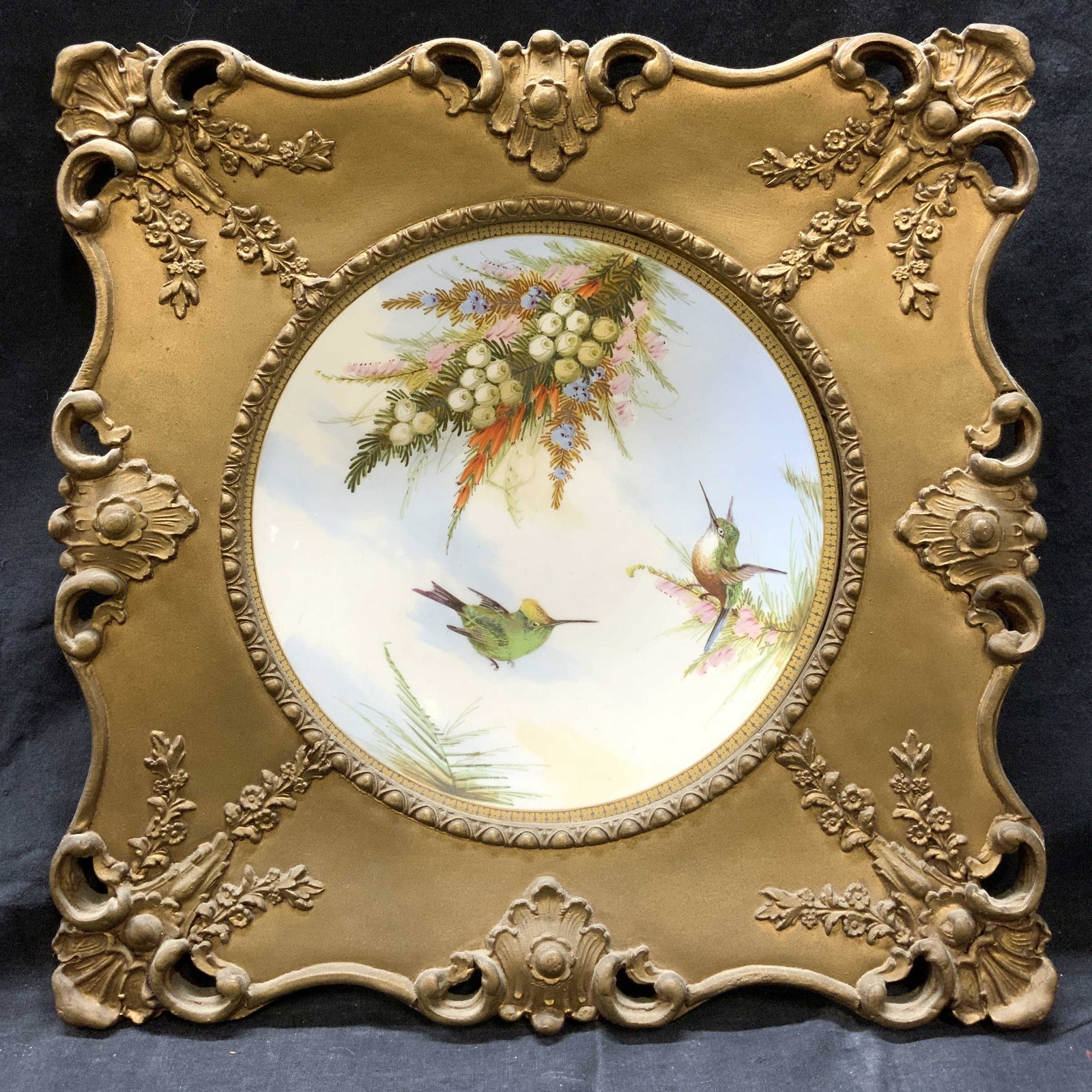 Antique Hand Painted Plate In Ornate Gilt Frame: Antique Hand Painted Plate in ornate gilt frame, no apparent inscriptions, subject shows cloudy blue sky with humming birds and floral leaves, in frame measures approx 14 1/2 x 14 1/2 in., gilt metal 