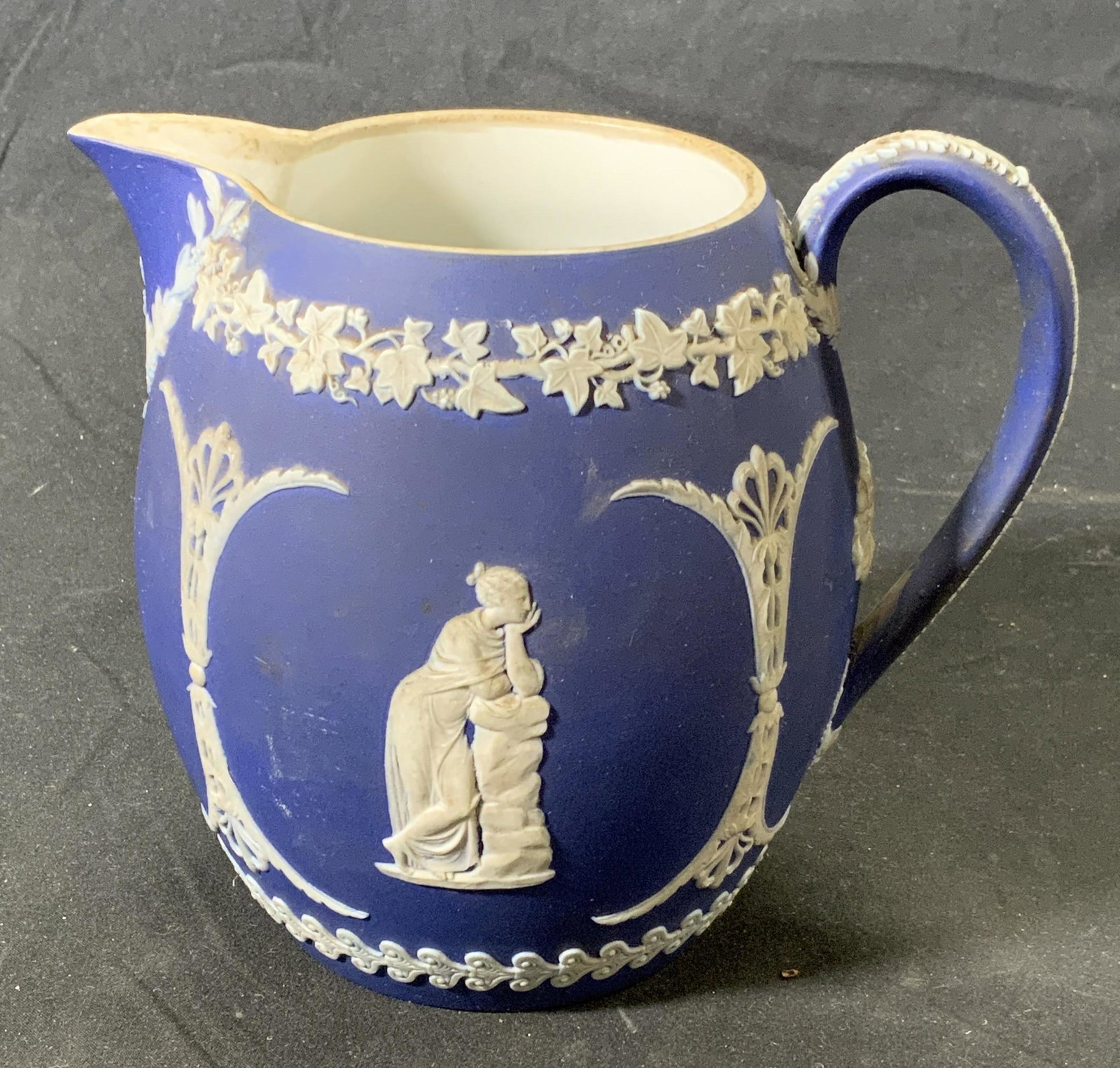 Vintage WEDGWOOD Royal Blue Jasperware Creamer: Vintage Wedgwood royal blue Jasperware creamer with with figural and grapevine relief decoration. Surface wear consistent with age and exposure. Measures approx. 5 inches diameter and 5.5 inches tall.