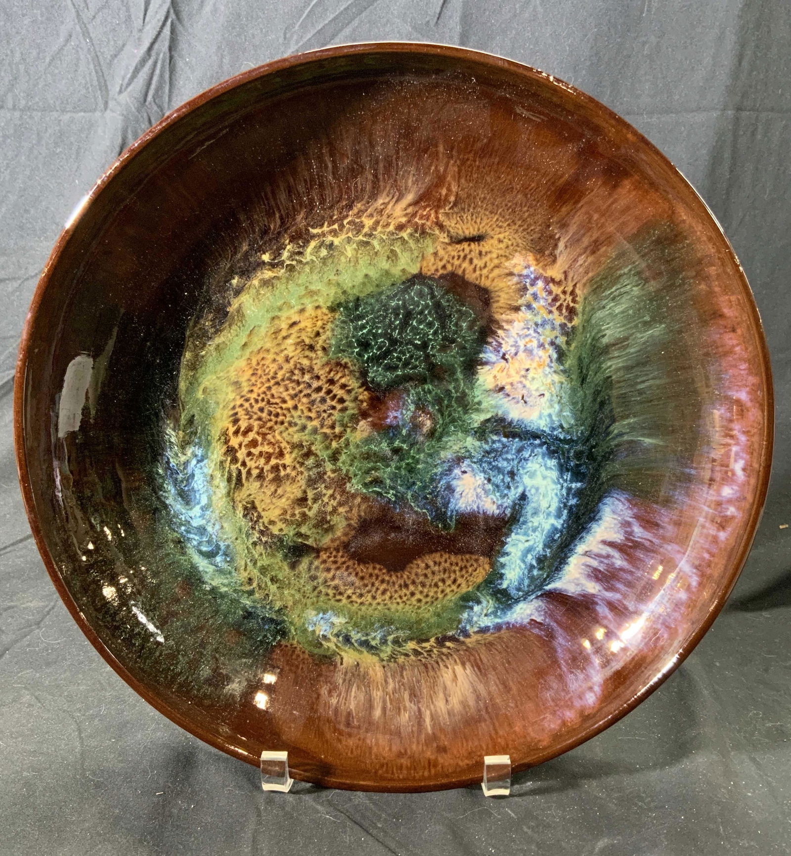 Vintage Art Pottery Dish, Poland: A vintage art pottery dish in hues of brown, green, and blue. Measures approx. 13.25 inches diameter. Wear to surface consistent with age and exposure. Made in Poland. Hole to back of plate for decora
