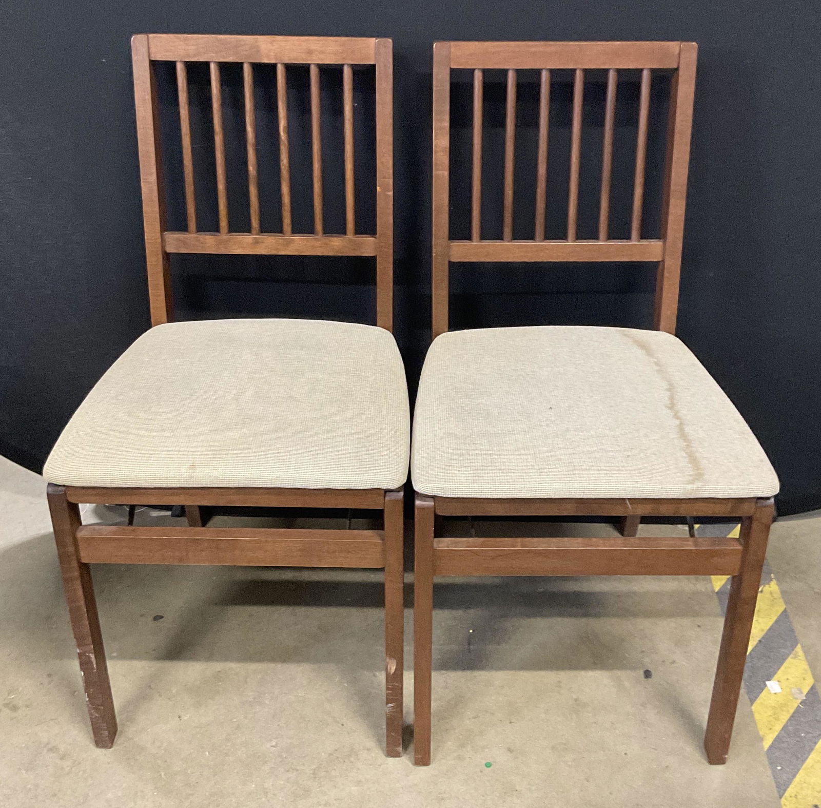 Pair STAKMORE CO. Vintage Folding Chairs: Rich brown hued mission style chairs with light hued upholstery. Soft hand upholstery. Chairs have spindle style cylindrical bar backing. Chairs fold with metal hardware. Discoloration to pieces surfa