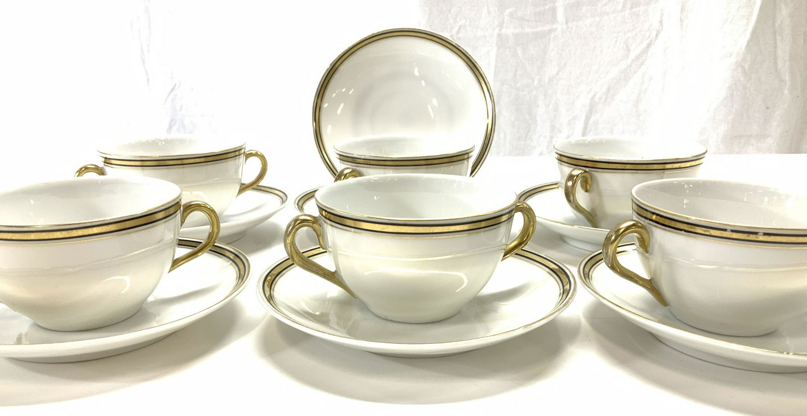 BASSET LIMOGES AUSTRIA porcelain Cups & Saucers 13: Set vintage Basset Limoges Austria Porcelain Cups and Saucers, White fine bone China with gilt and black stripe edge and gilt handles. Dual handle cups, perfect for tea or dessert, 6 cups , 5 in total